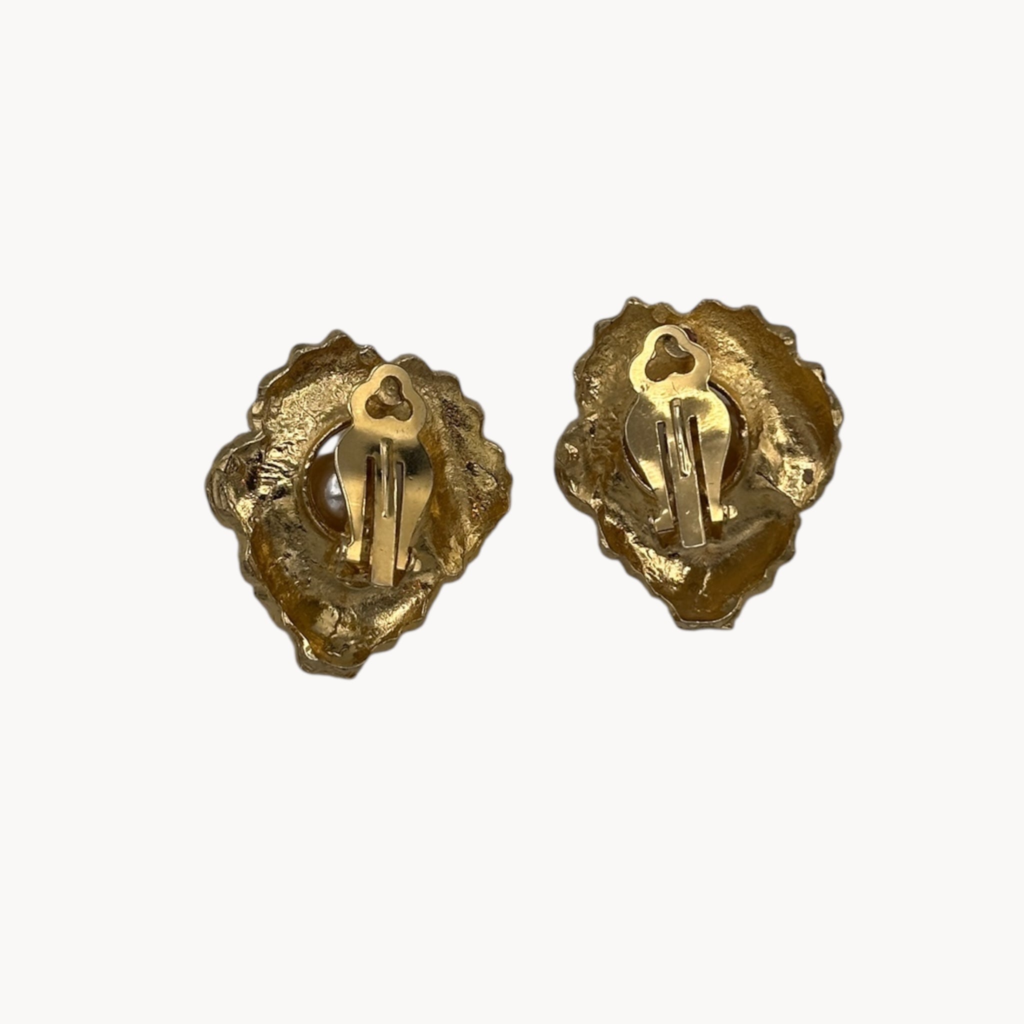 Back view of Vintage unmarked clip-on earrings with textured gold-tone floral design, faux pearl center, and crystal accents, 1980s bridal jewelry.