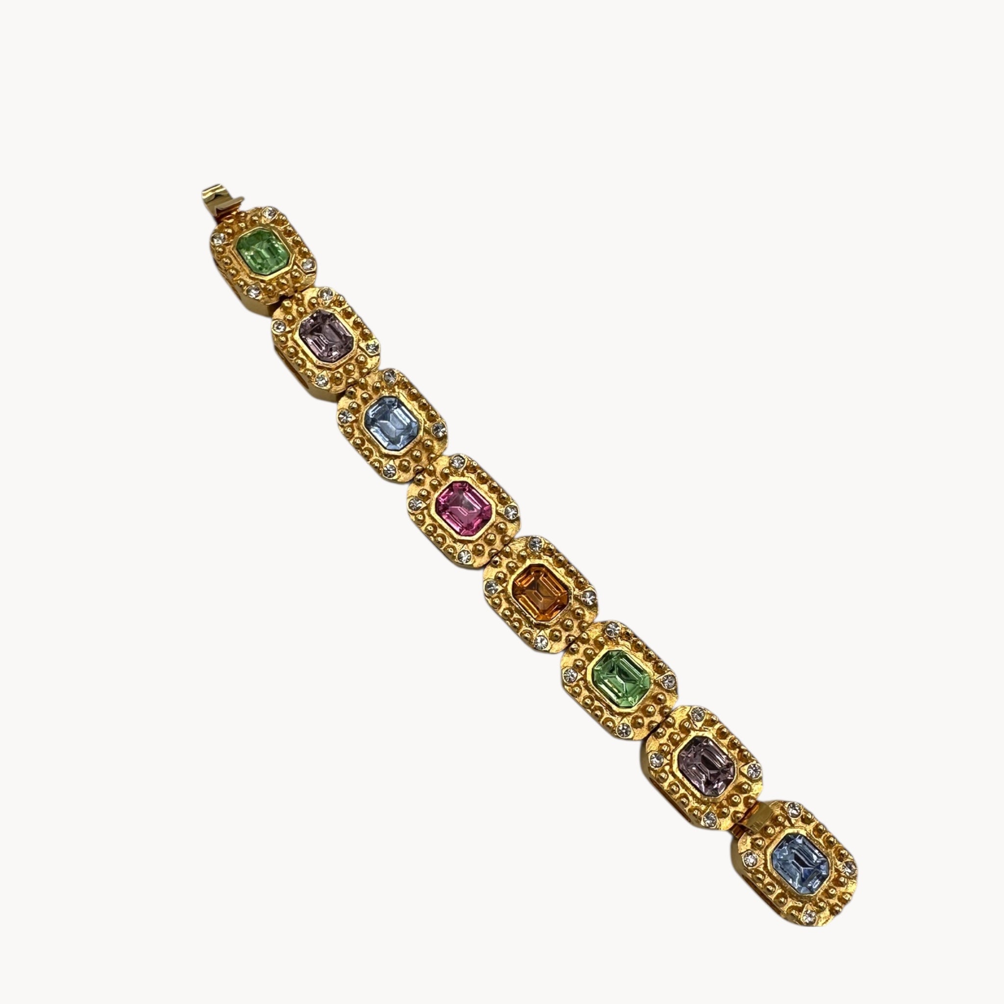 Flat lay view Vintage Kenneth Jay Lane bracelet with multicolor emerald-cut rhinestones framed in gold-tone and pavé crystals, 1980s–1990s statement jewelry.