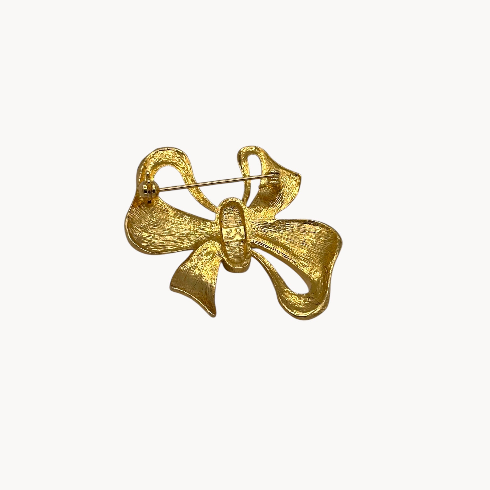 Gold bow-shaped brooch on a white background