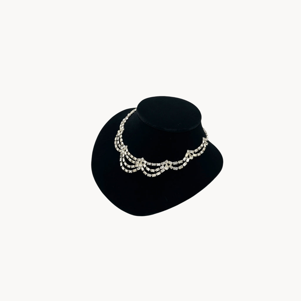 Side view of Mid-century draped rhinestone necklace with tiered design displayed on black bust.