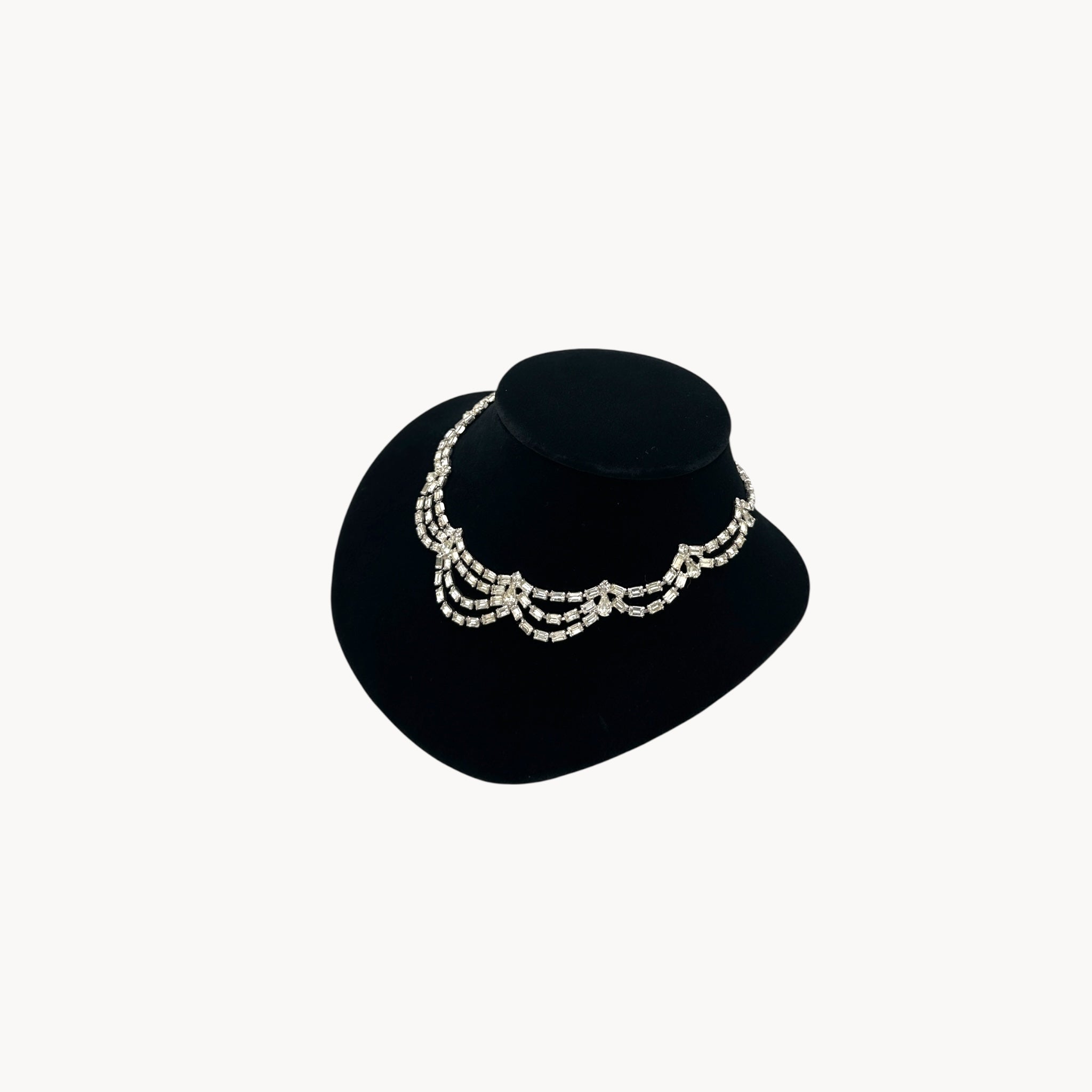 Side view of Mid-century draped rhinestone necklace with tiered design displayed on black bust.