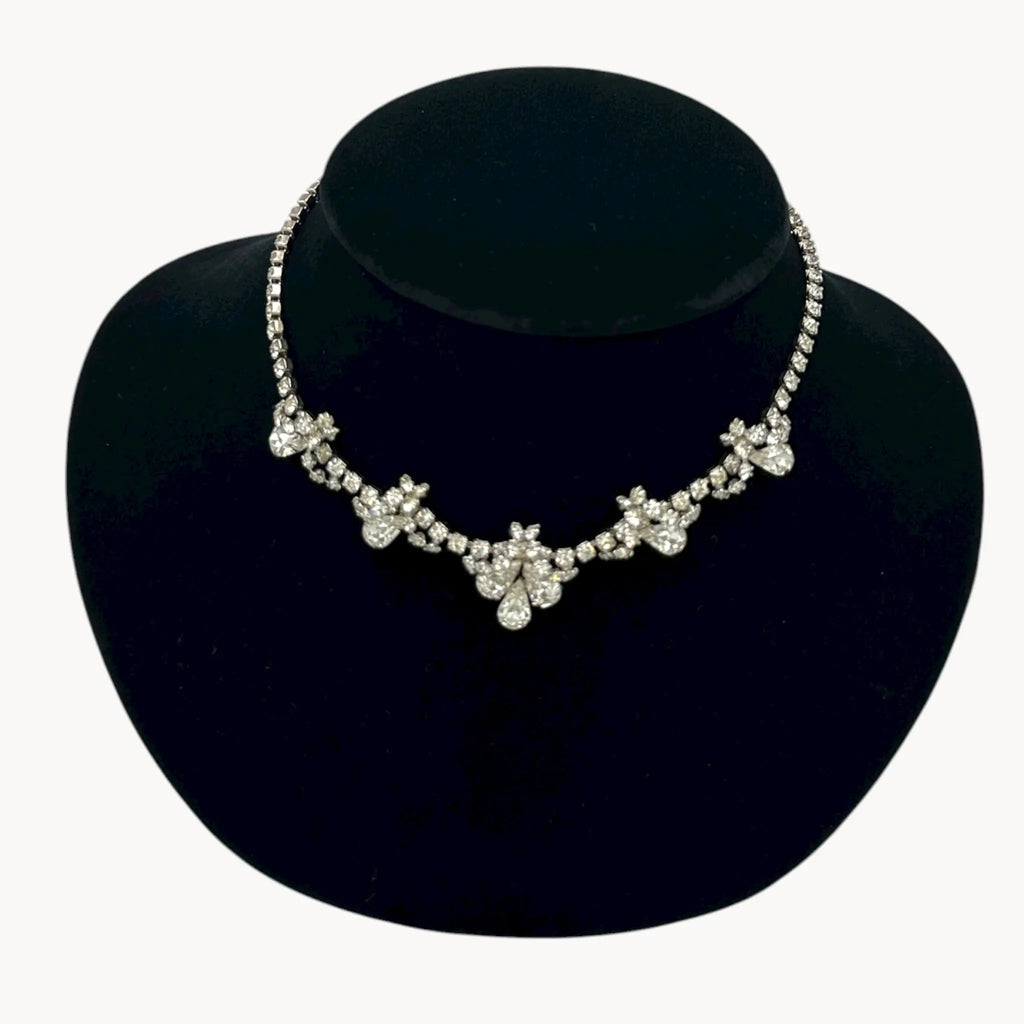 Close up view of Vintage mid-century teardrop rhinestone necklace with graduated clear crystals on silver setting displayed on black velvet bust