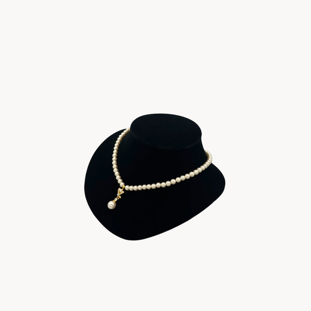 Side view of Vintage Napier faux pearl necklace with rhinestone X motif and pearl drop pendant.