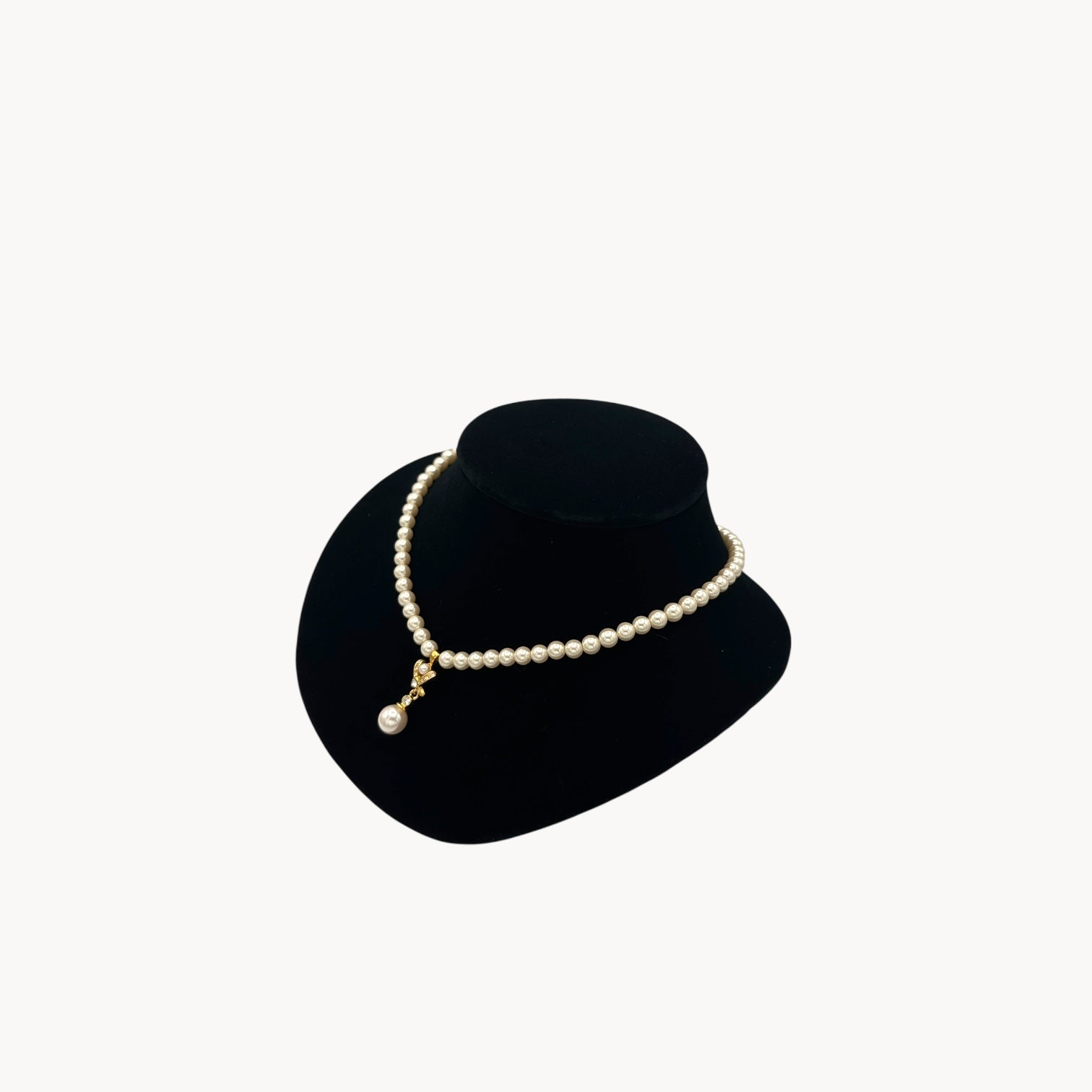 Side view of Vintage Napier faux pearl necklace with rhinestone X motif and pearl drop pendant.