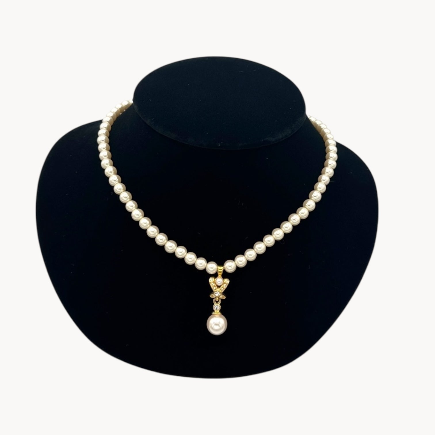 Close up view of Vintage Napier faux pearl necklace with rhinestone X motif and pearl drop pendant.