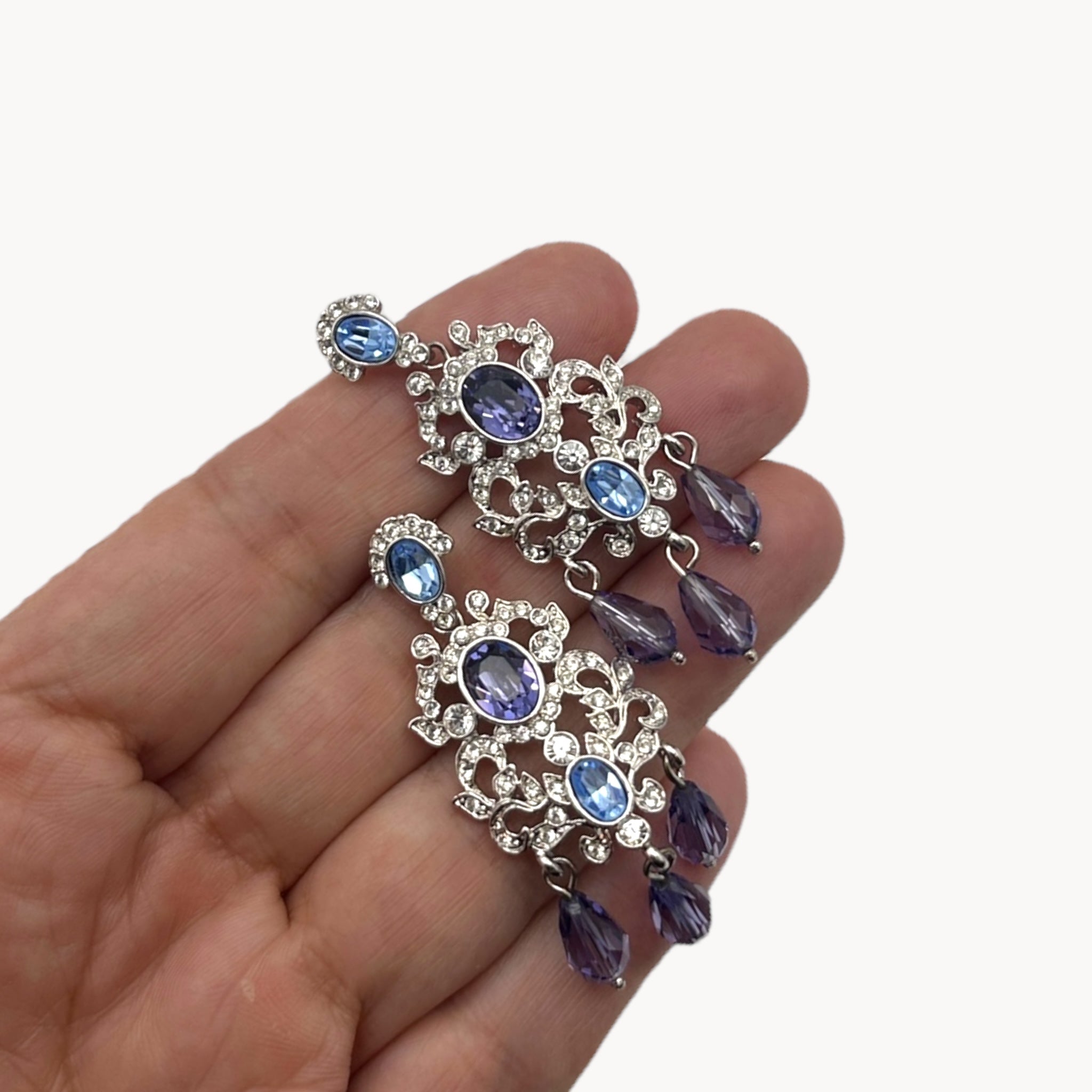 Scale view of Vintage Nolan Miller blue crystal dangle pierced earrings with chandelier design
