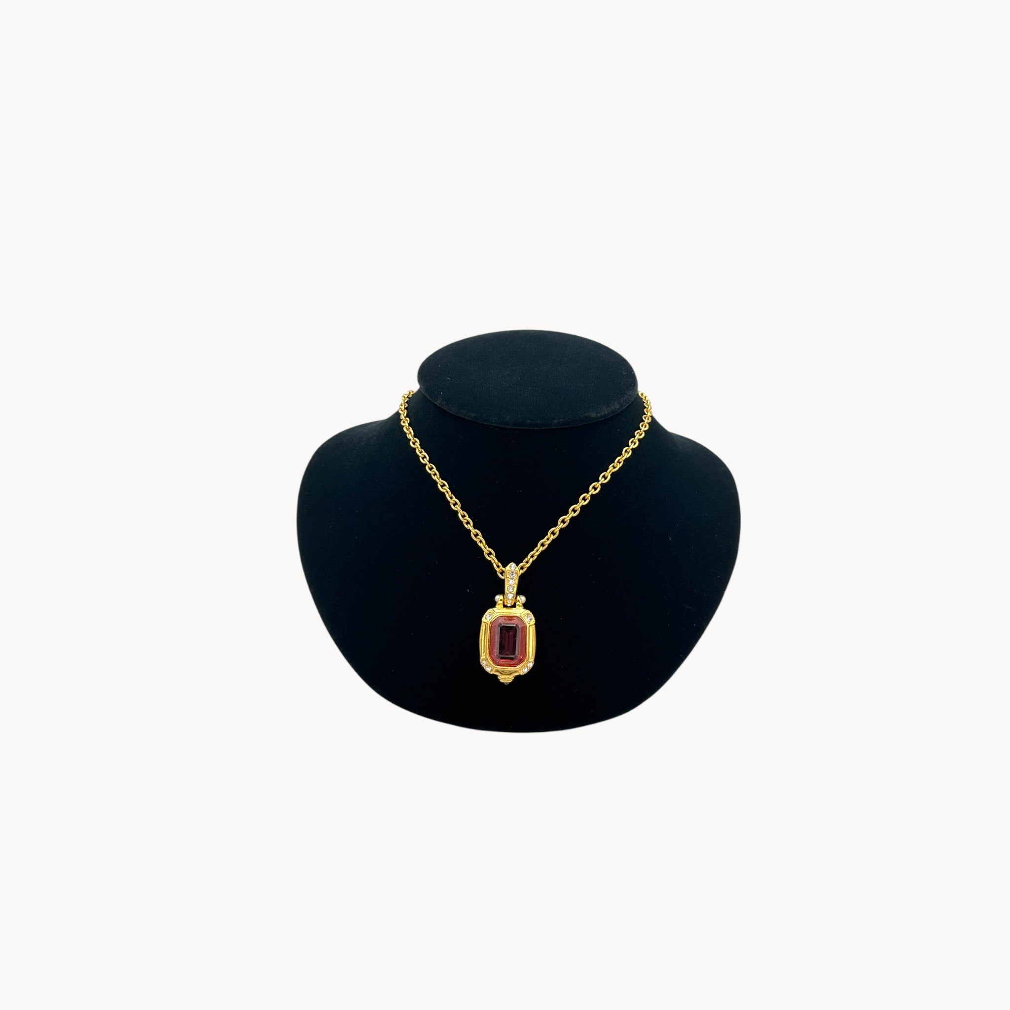 Vintage Nolan Miller long gold chain necklace with pink crystal pendant and clear crystal accents, 1980s–1990s bridal jewelry shown on black bust.