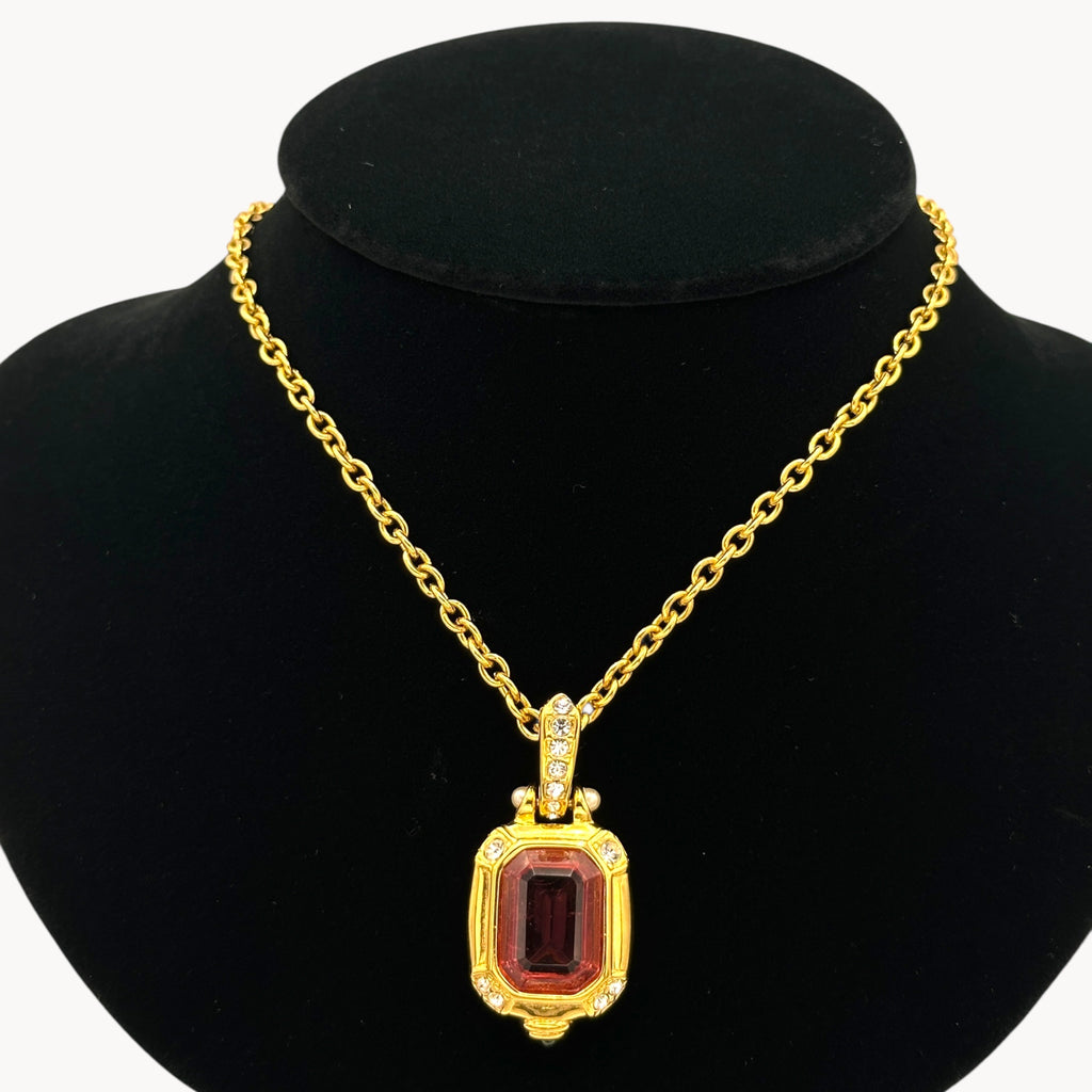 Close up view of Vintage Nolan Miller long gold chain necklace with pink crystal pendant and clear crystal accents, 1980s–1990s bridal jewelry shown on black bust.