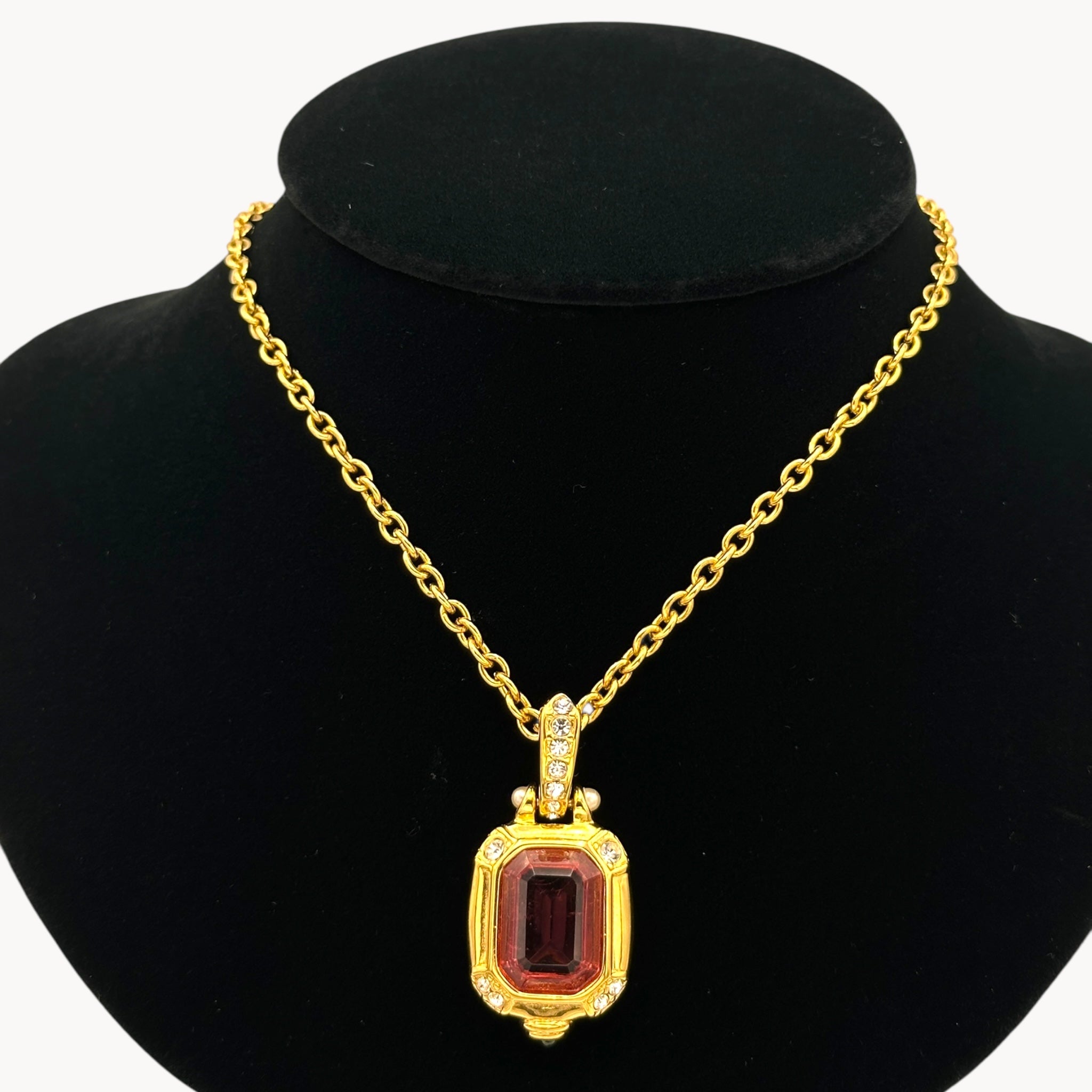 Close up view of Vintage Nolan Miller long gold chain necklace with pink crystal pendant and clear crystal accents, 1980s–1990s bridal jewelry shown on black bust.