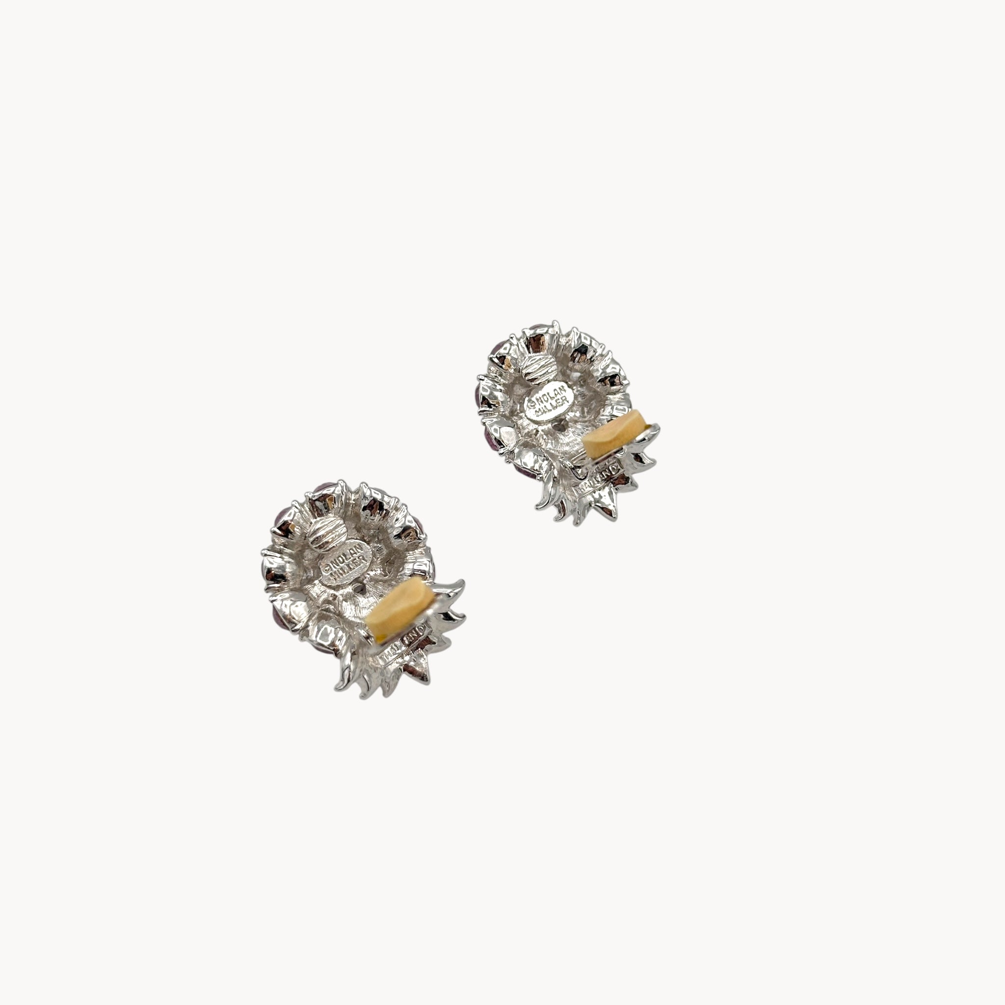 Back view with clips open of Vintage Nolan Miller rhinestone floral clip-on earrings with silver-tone leaves