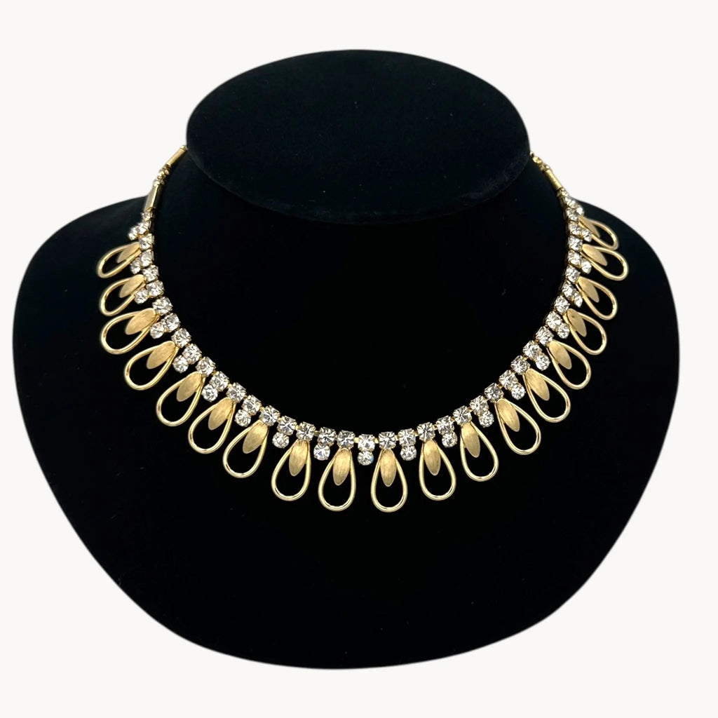 Close up view of Vintage Sarah Coventry gold-tone teardrop bib necklace with clear rhinestones displayed on black velvet bust