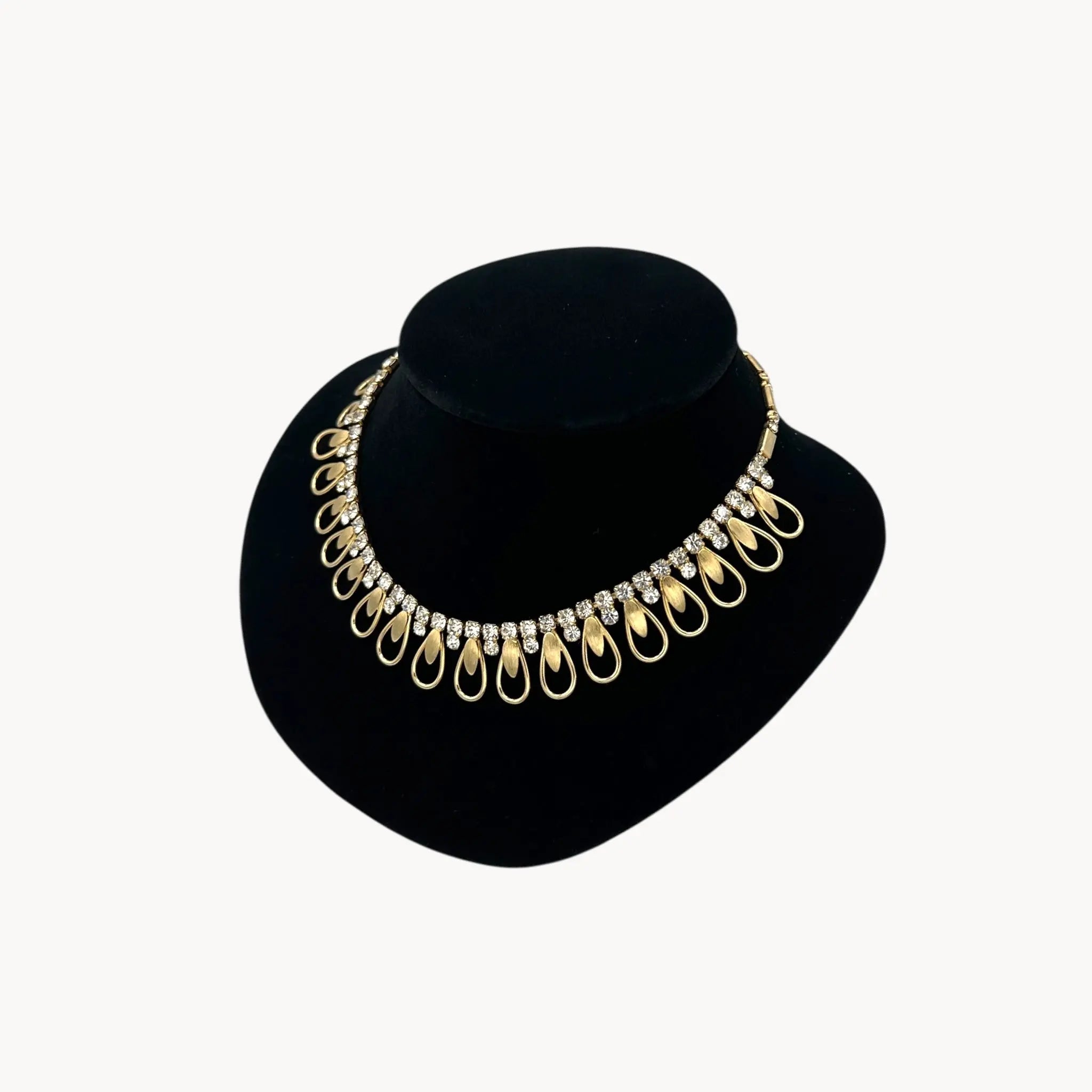 Side view of Vintage Sarah Coventry gold-tone teardrop bib necklace with clear rhinestones displayed on black velvet bust