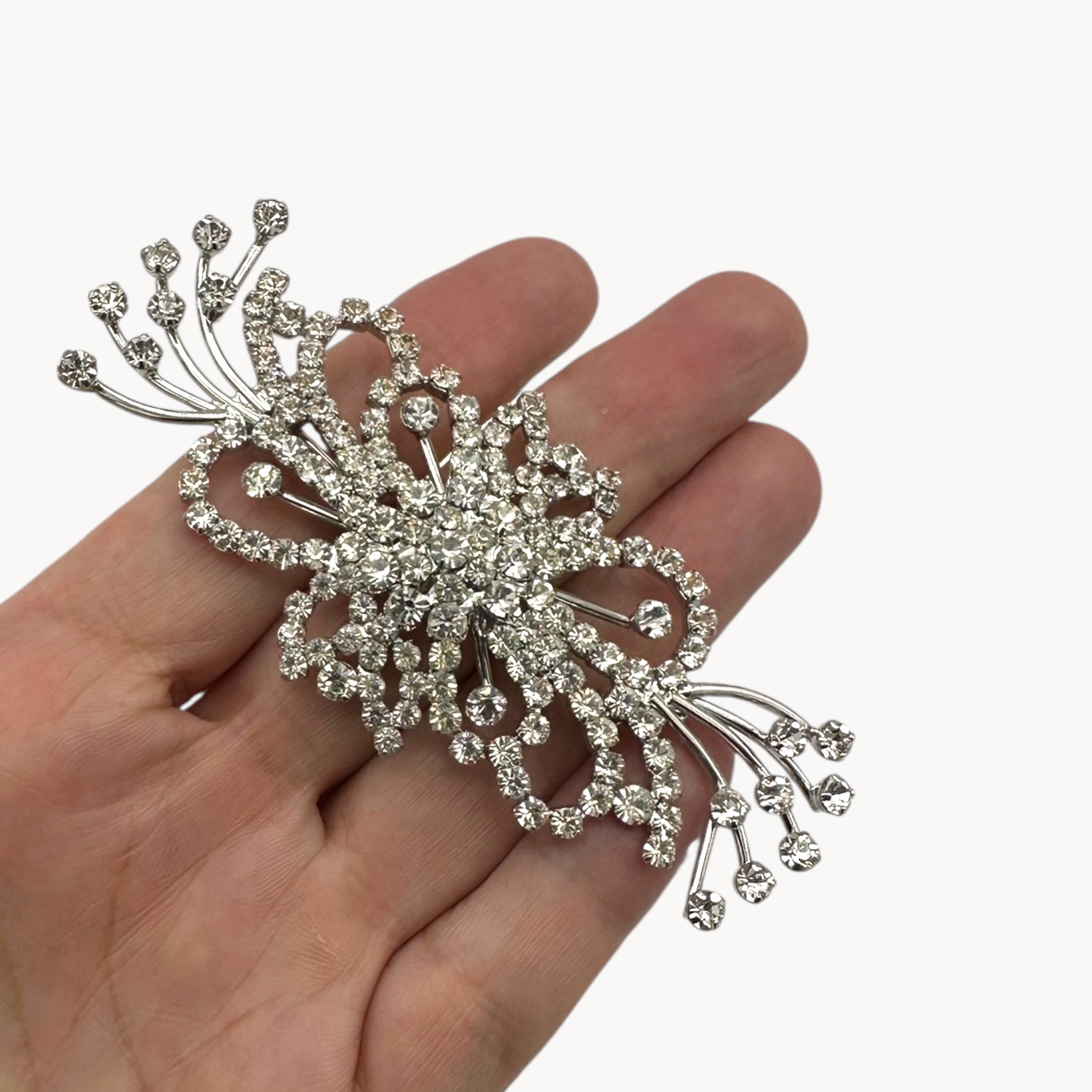 Scale size image of Large vintage rhinestone spray brooch with prong-set stones and rhodium plating, mid-century design.