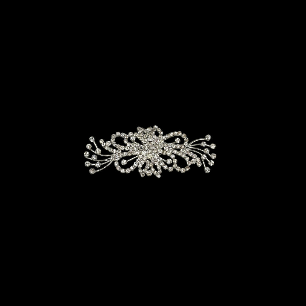 On black background Large vintage rhinestone spray brooch with prong-set stones and rhodium plating, mid-century design.
