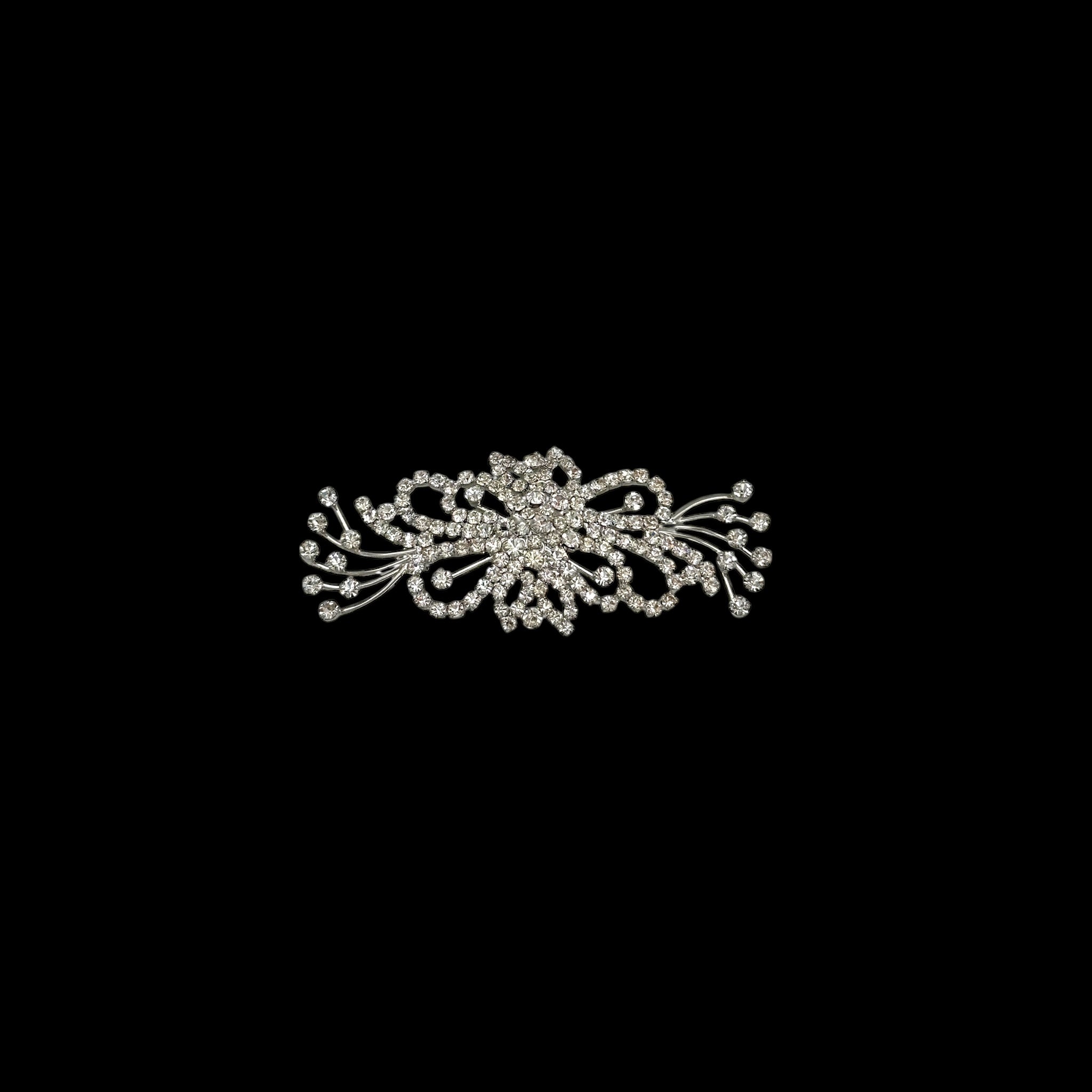 On black background Large vintage rhinestone spray brooch with prong-set stones and rhodium plating, mid-century design.