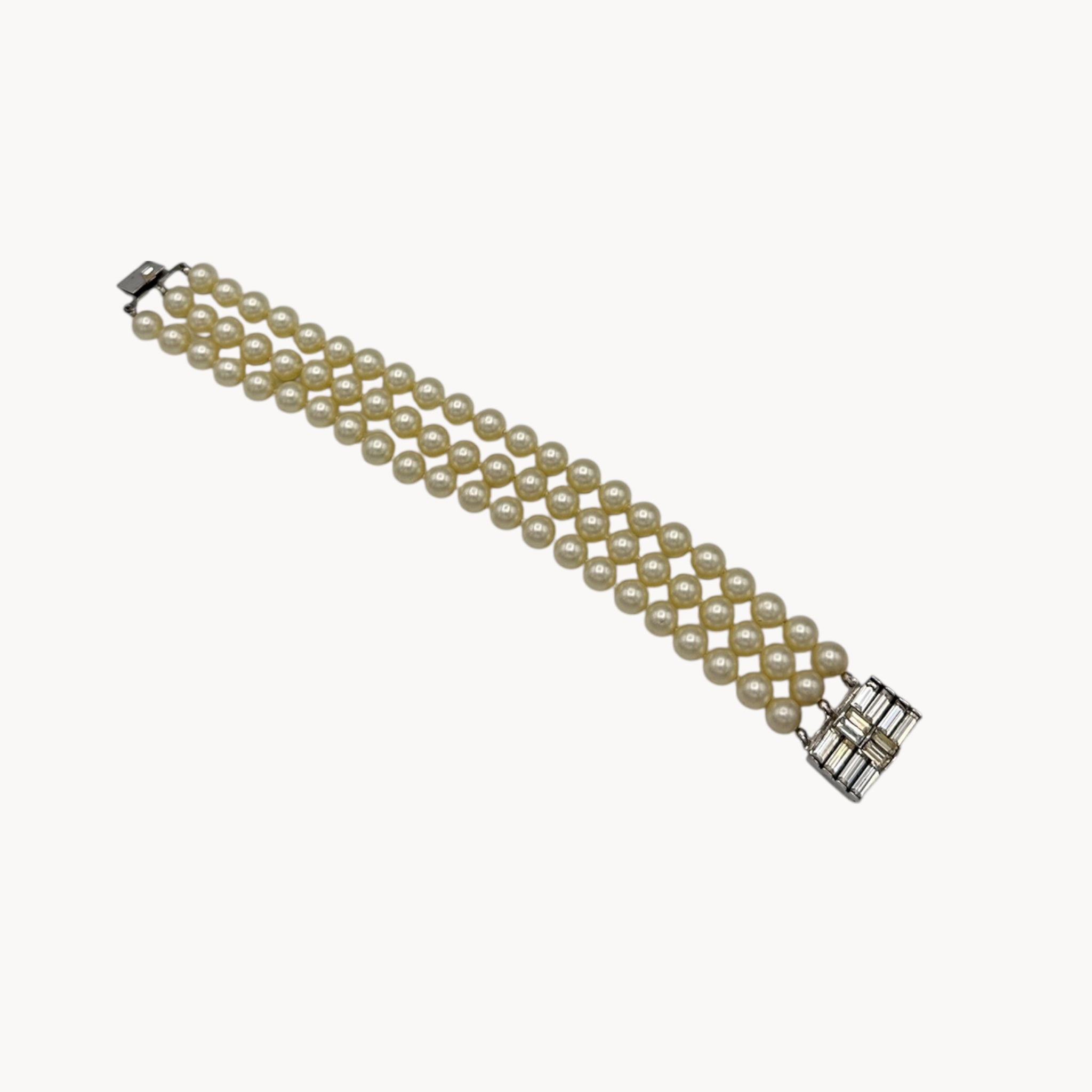 Flat lay view Vintage Trifari faux pearl triple-strand bracelet with baguette crystal clasp, 1950s–1960s bridal jewelry