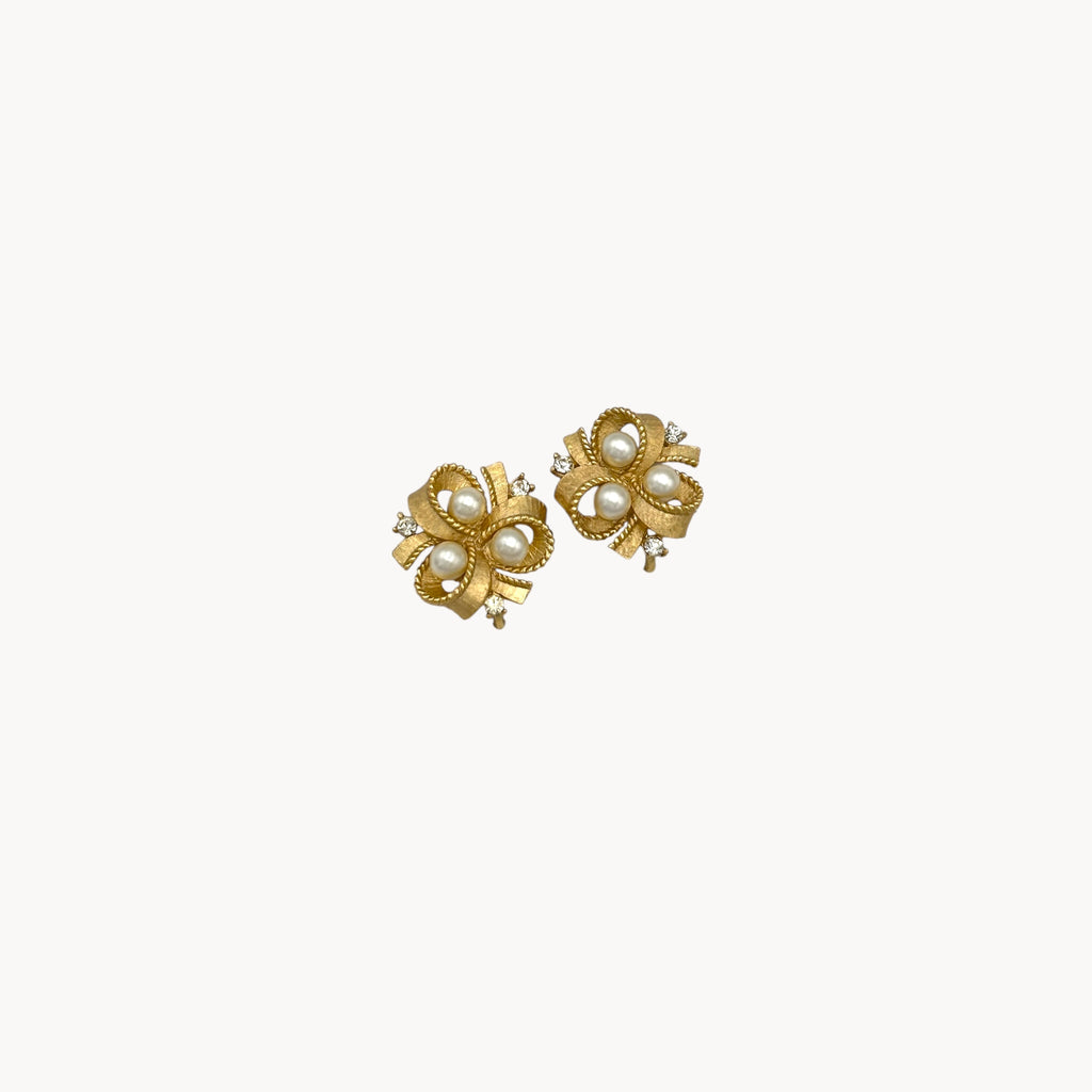 zoom in Vintage Trifari clip-on earrings with gold bow design, faux pearls, and crystal accents, 1960s bridal jewelry.