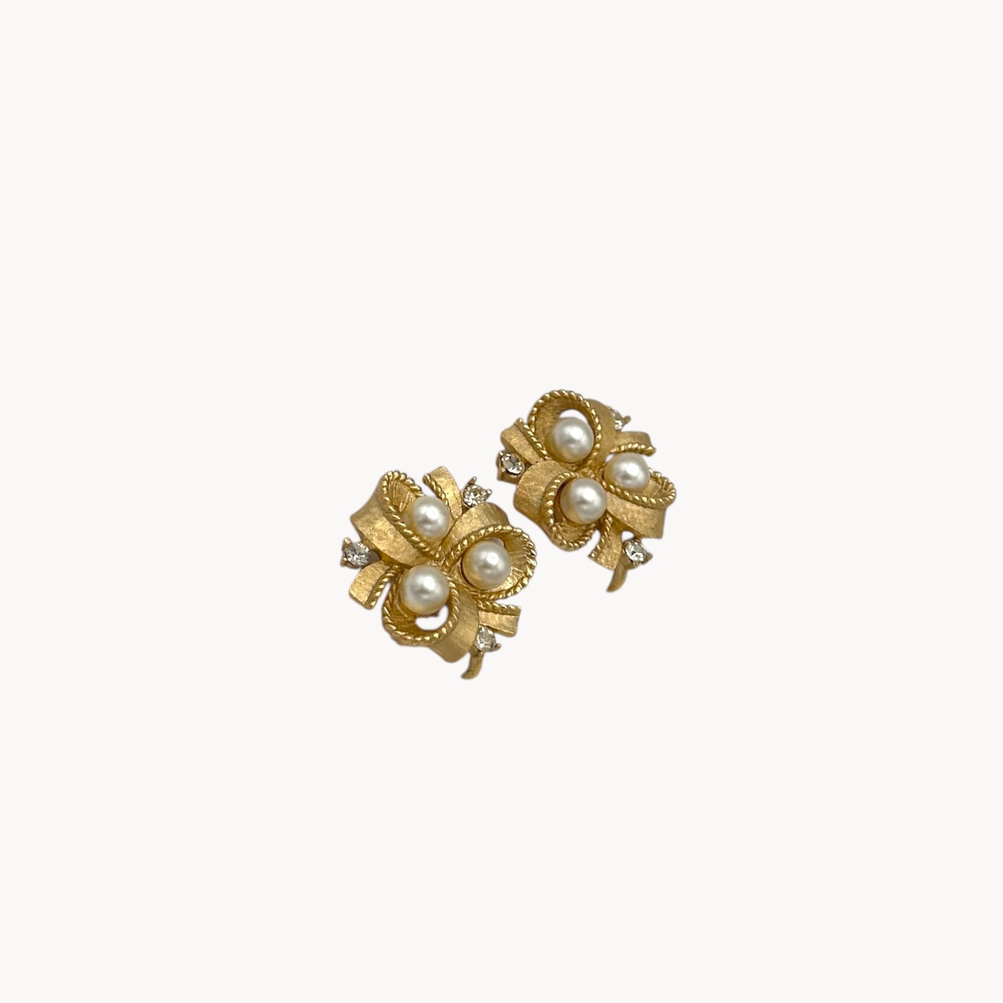 side view Vintage Trifari clip-on earrings with gold bow design, faux pearls, and crystal accents, 1960s bridal jewelry.
