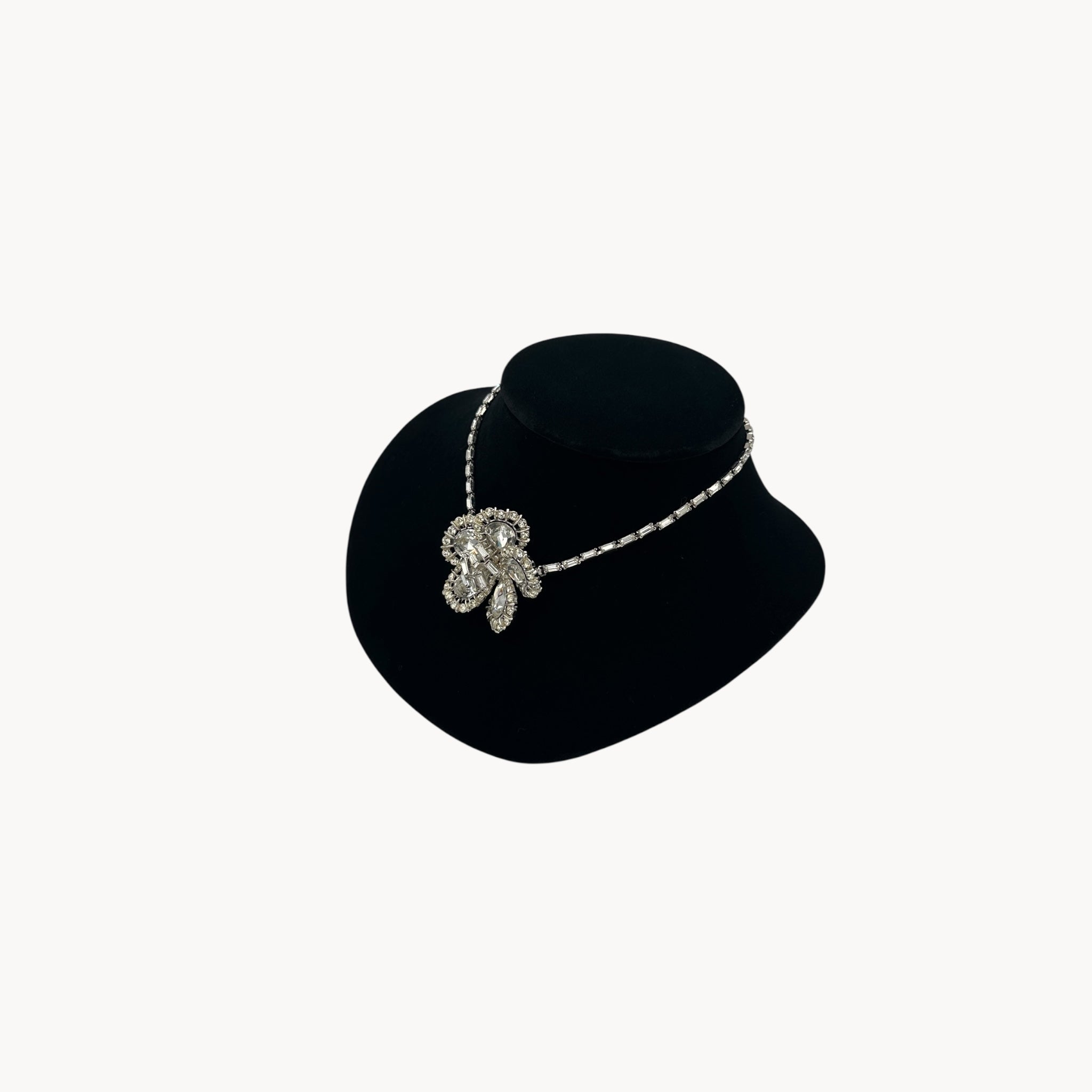 Side view of Large Trifari Rhinestone Floral Necklace on black bust.