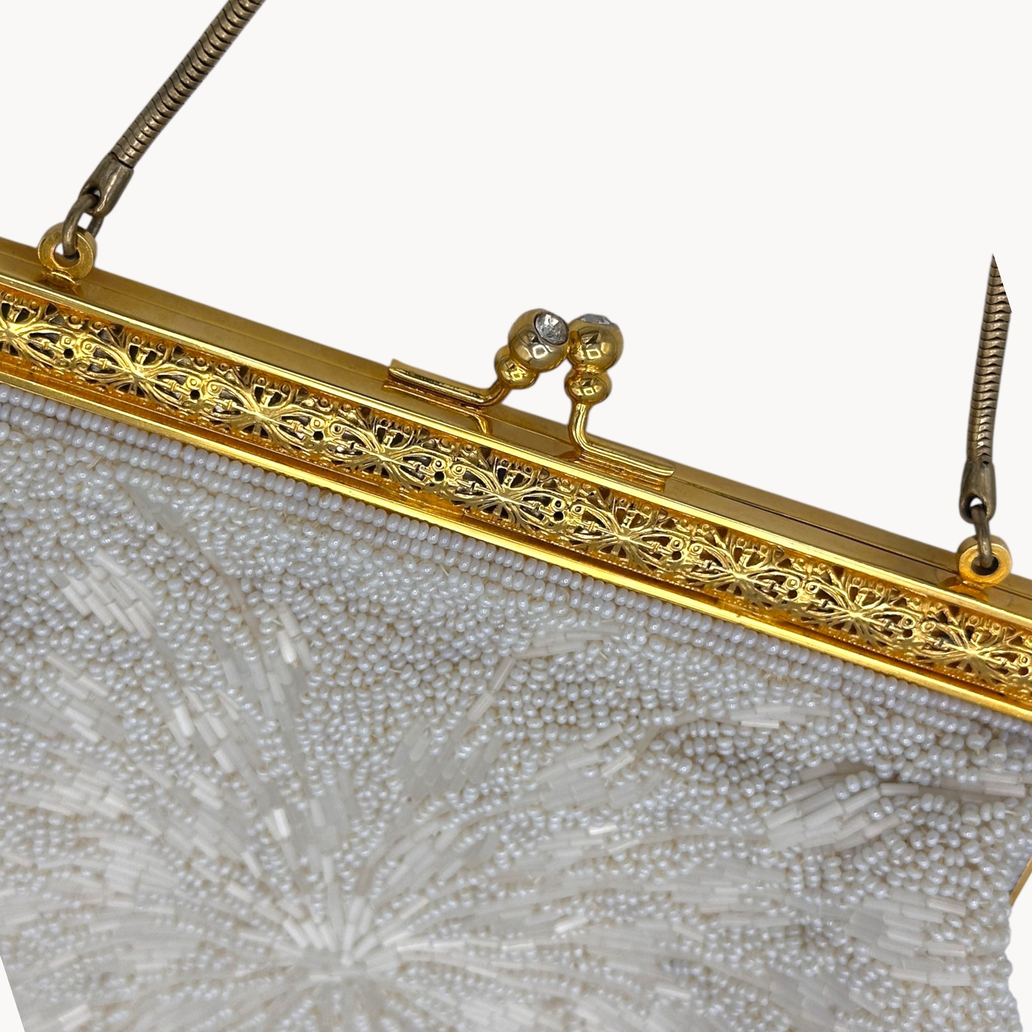 Close-up of a beaded handbag with a gold frame on a white background