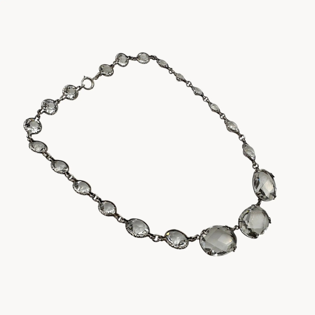 Side view of Vintage Art Deco crystal necklace with round and oval-cut crystals, stones on white background.