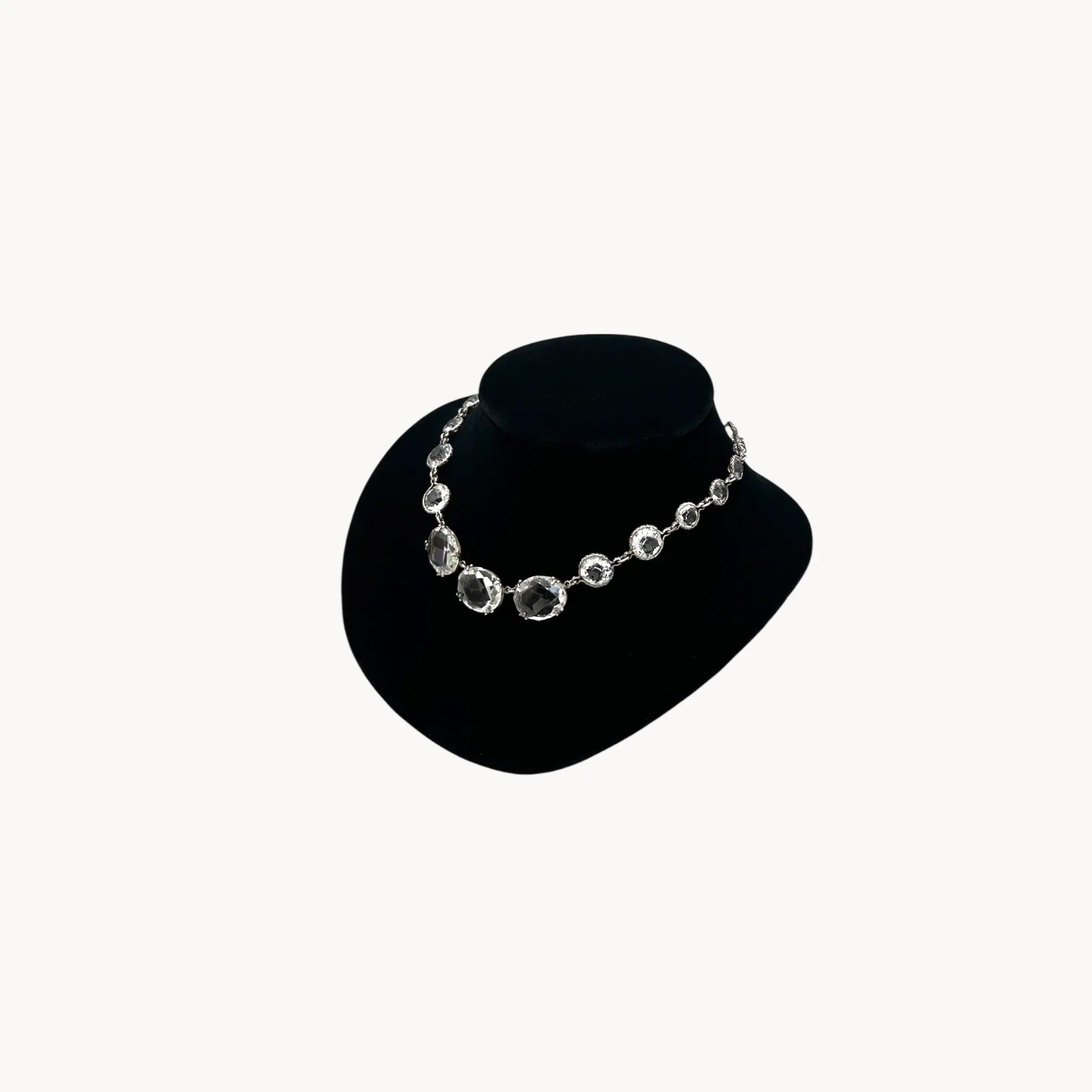 Side view of Vintage Art Deco crystal necklace with round and oval-cut crystals, stones on black bust.