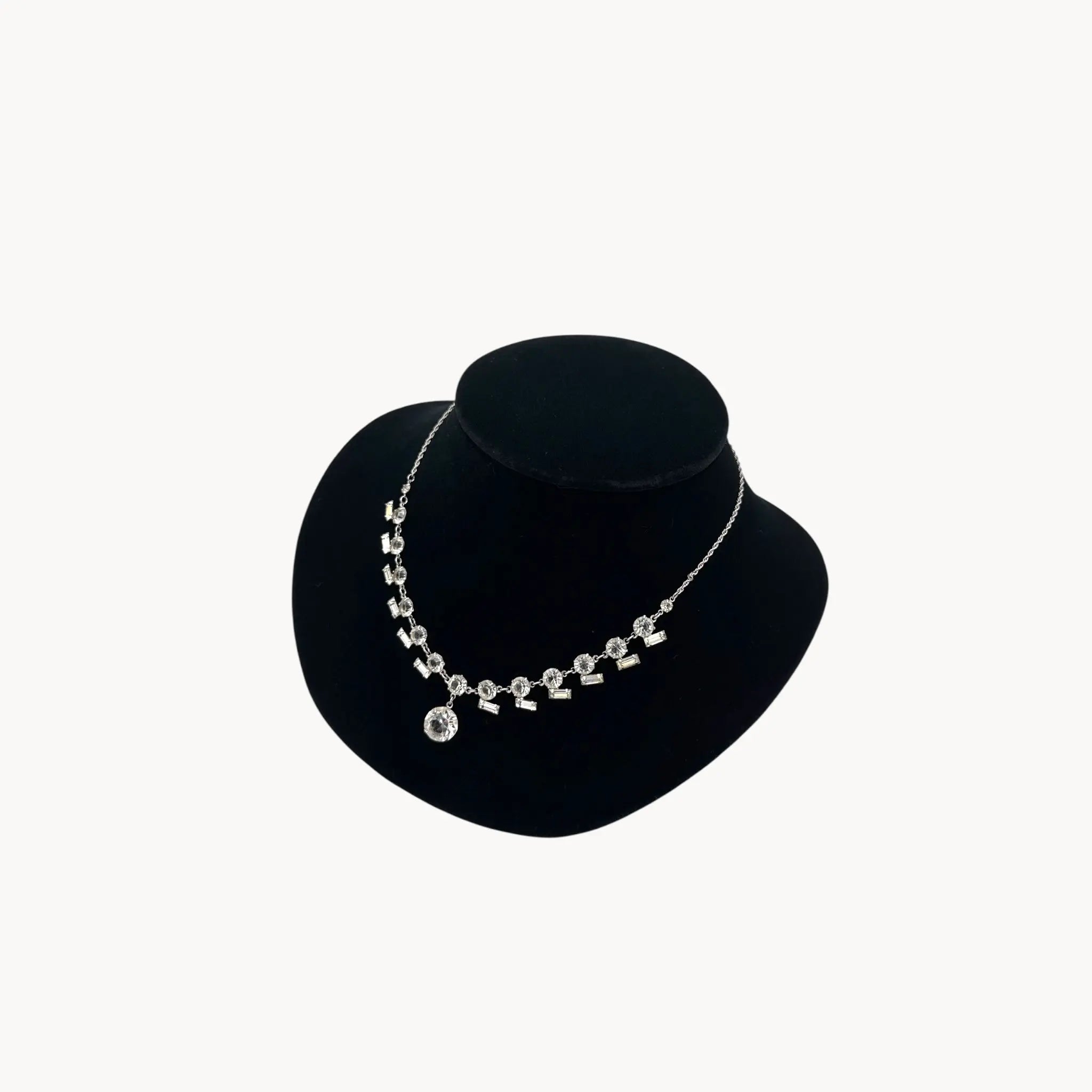 Side view of Art Deco sterling silver clear crystal necklace with geometric design and round drop.