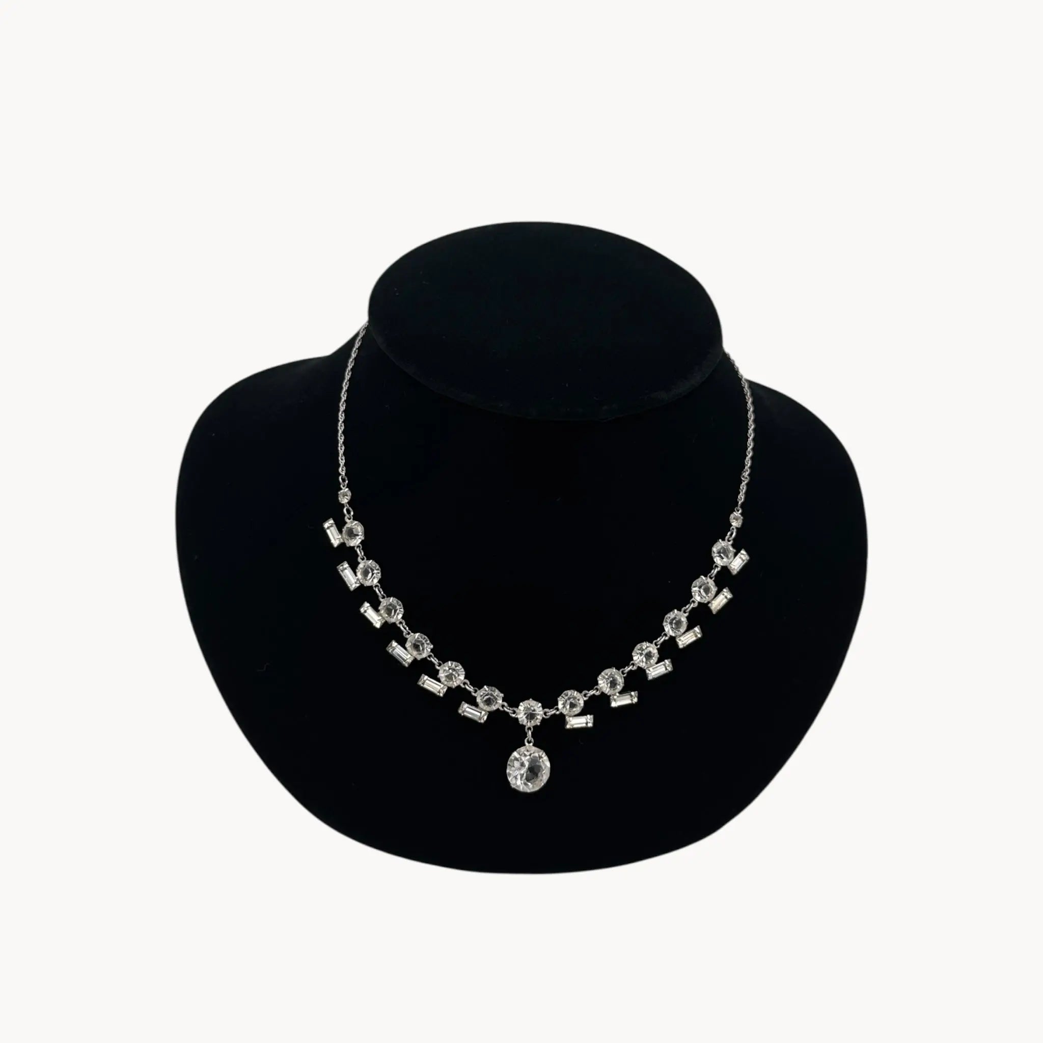 Close up view of Art Deco sterling silver clear crystal necklace with geometric design and round drop.