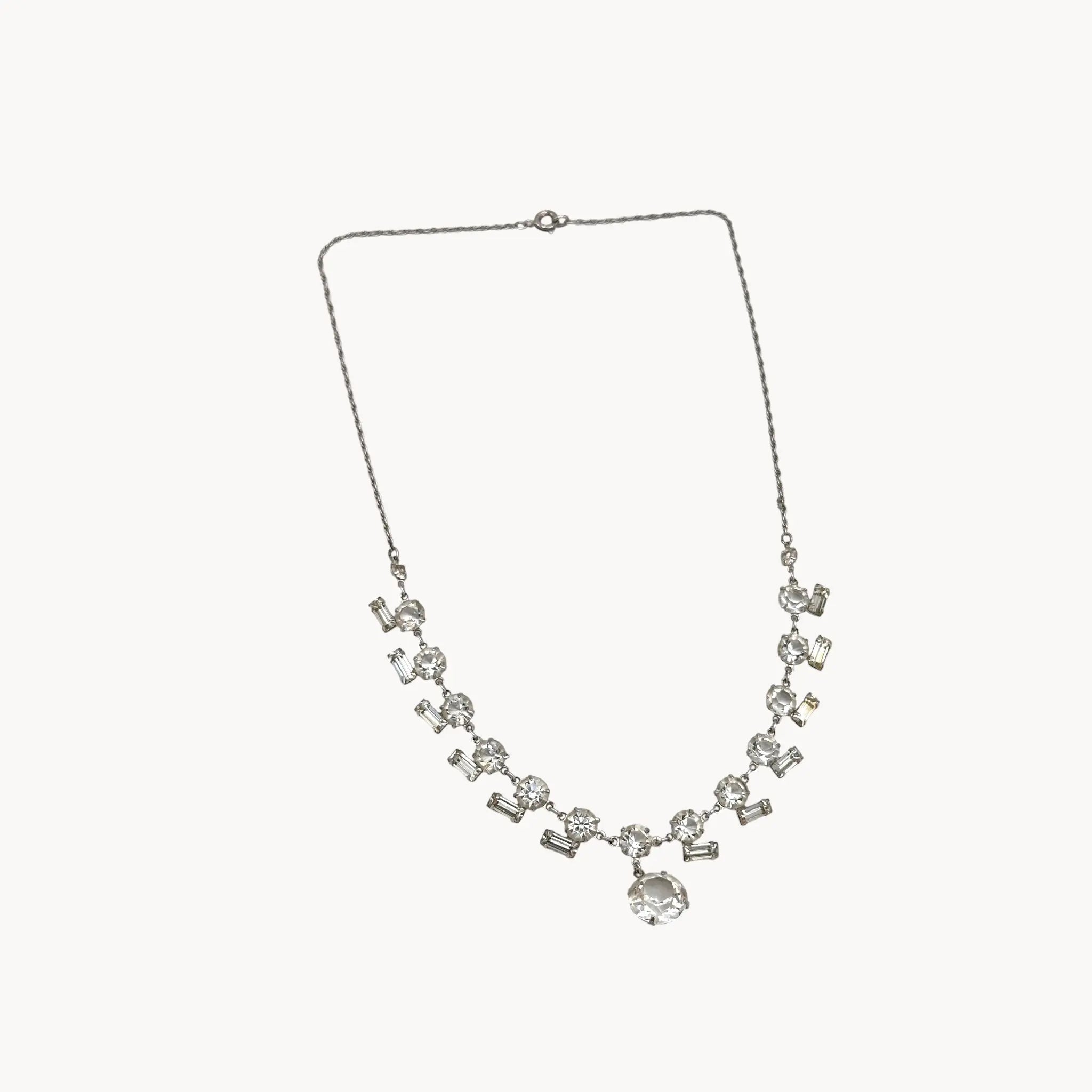 View against white background Art Deco sterling silver clear crystal necklace with geometric design and round drop.