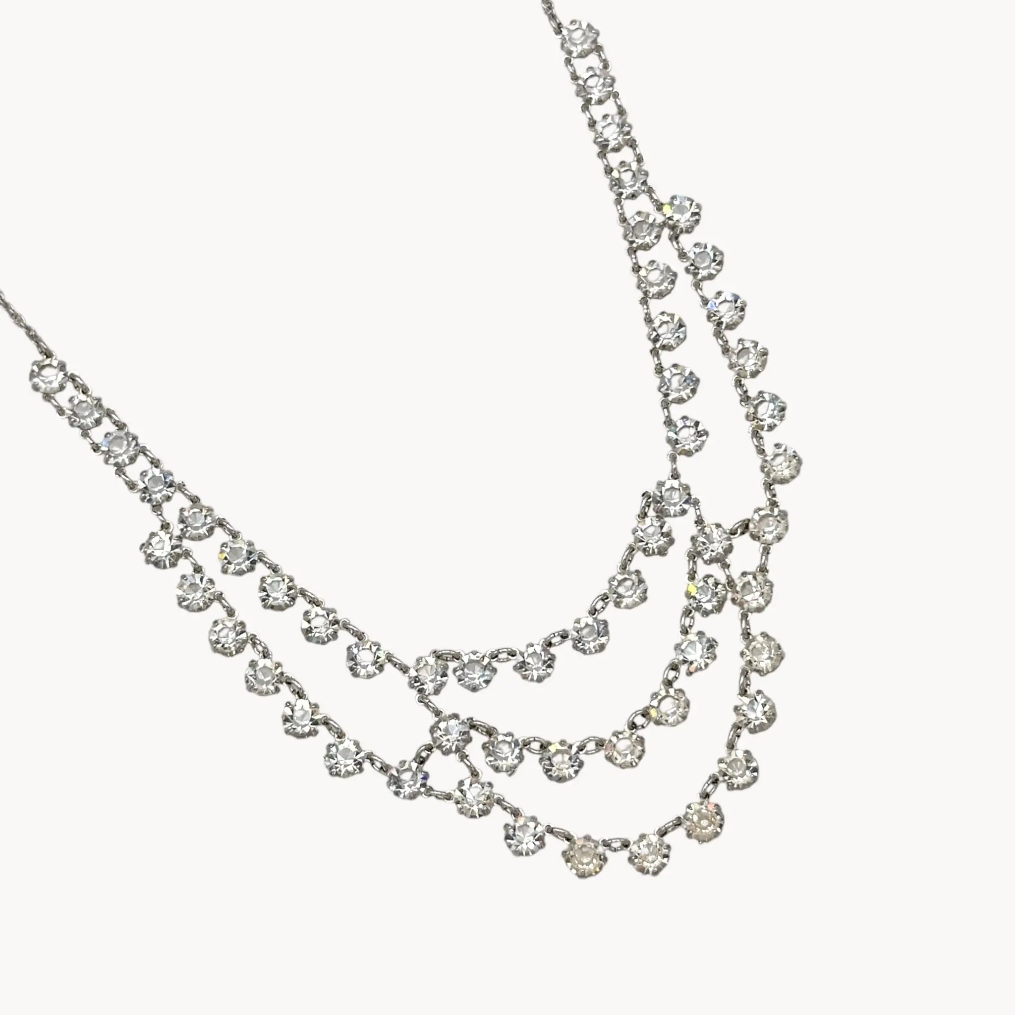 Close up view of drapping of Art Deco style 12K gold-filled rhodium plated crystal draped necklace on white background.