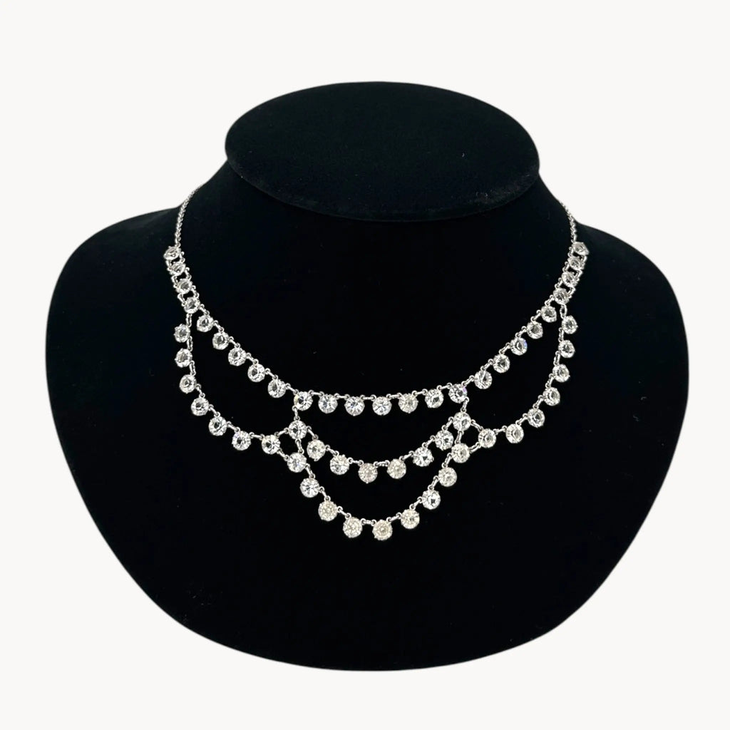 Close up view of Art Deco style 12K gold-filled rhodium plated crystal draped necklace on black bust.