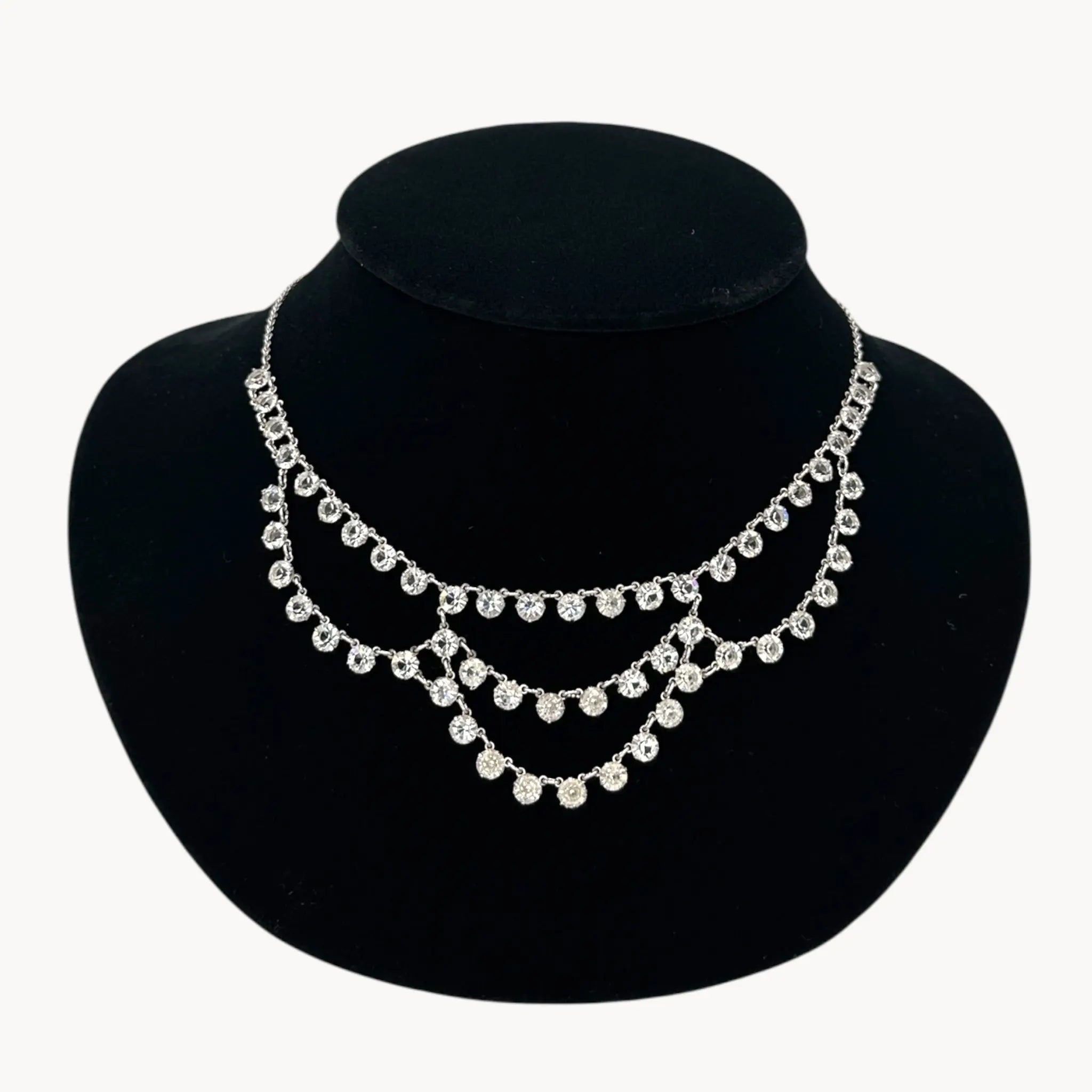 Close up view of Art Deco style 12K gold-filled rhodium plated crystal draped necklace on black bust.