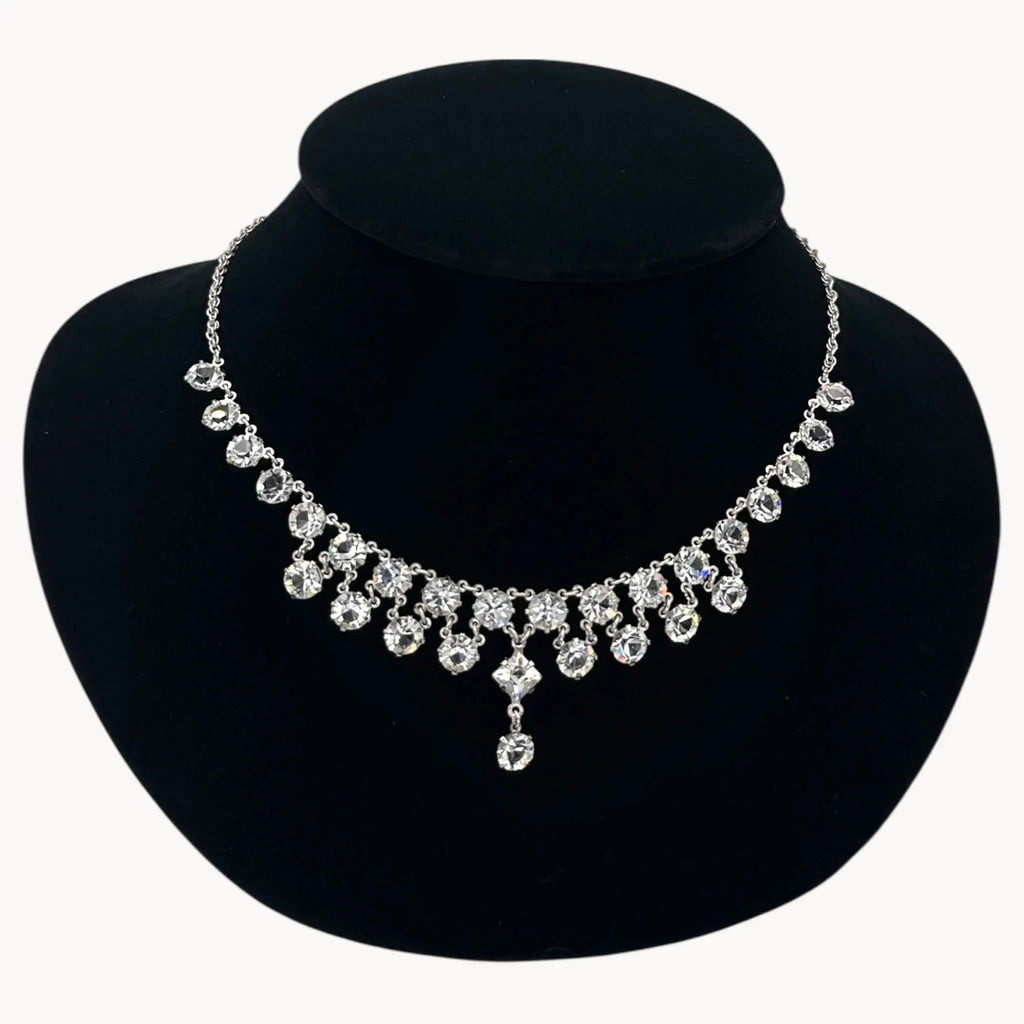 Close up view of Art Deco style rhodium plated crystal fringe necklace on black bust.