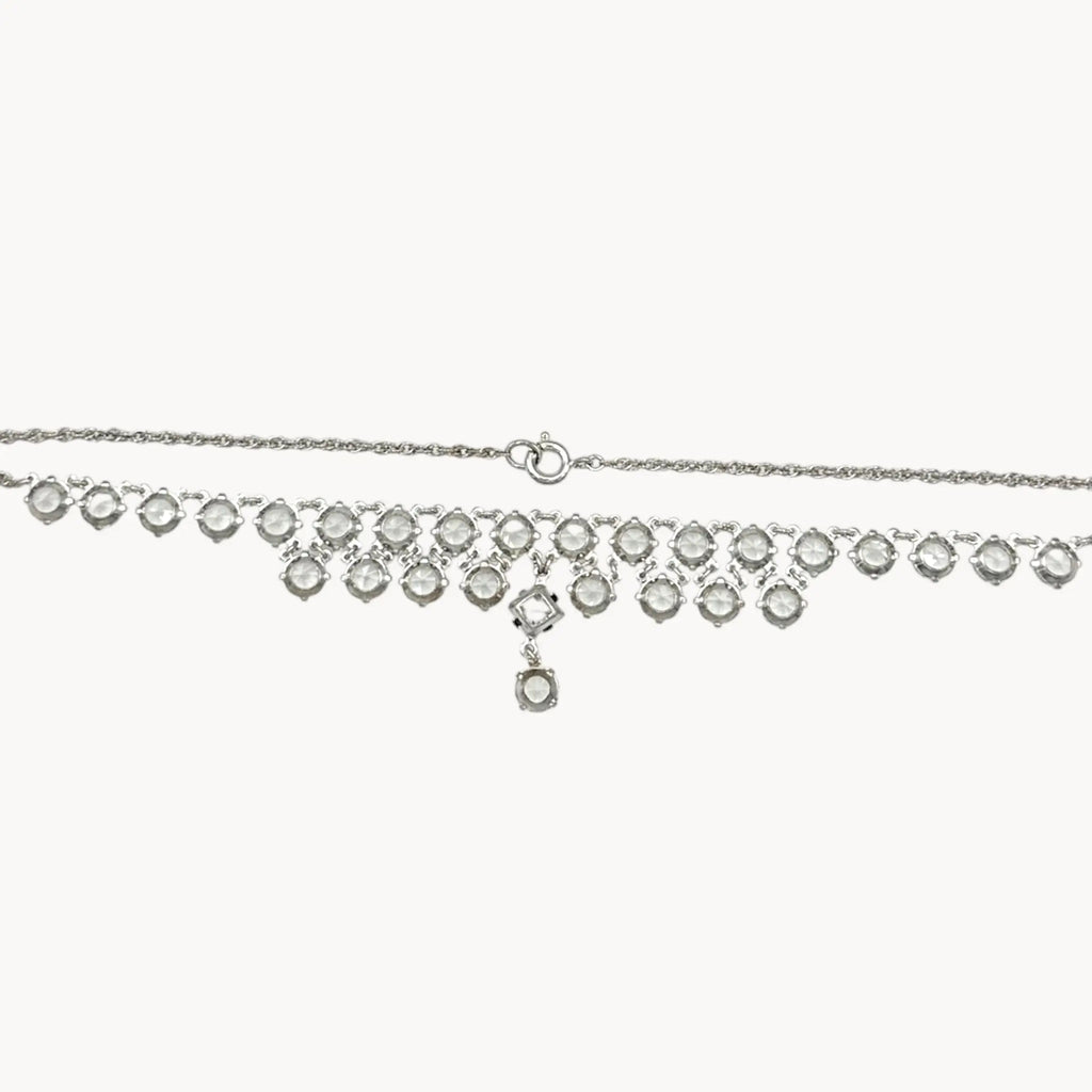 Back view of Art Deco style rhodium plated crystal fringe necklace on white background.