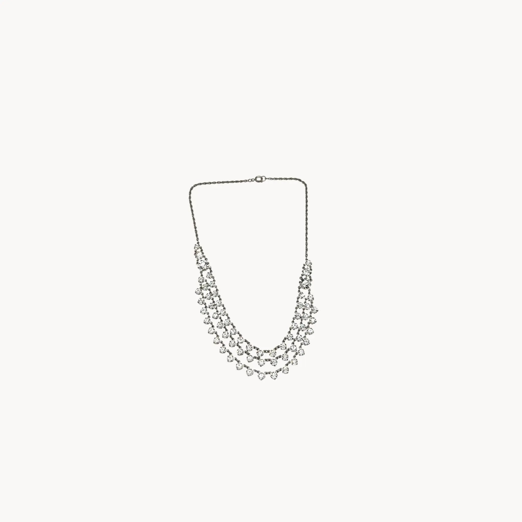 Art Deco style rhodium plated three-row crystal draped necklace on white background.