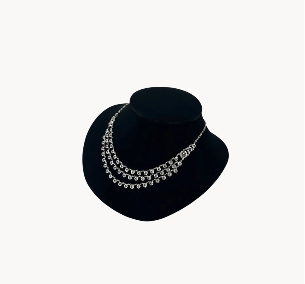 Side view of Art Deco style rhodium plated three-row crystal draped necklace on black bust.
