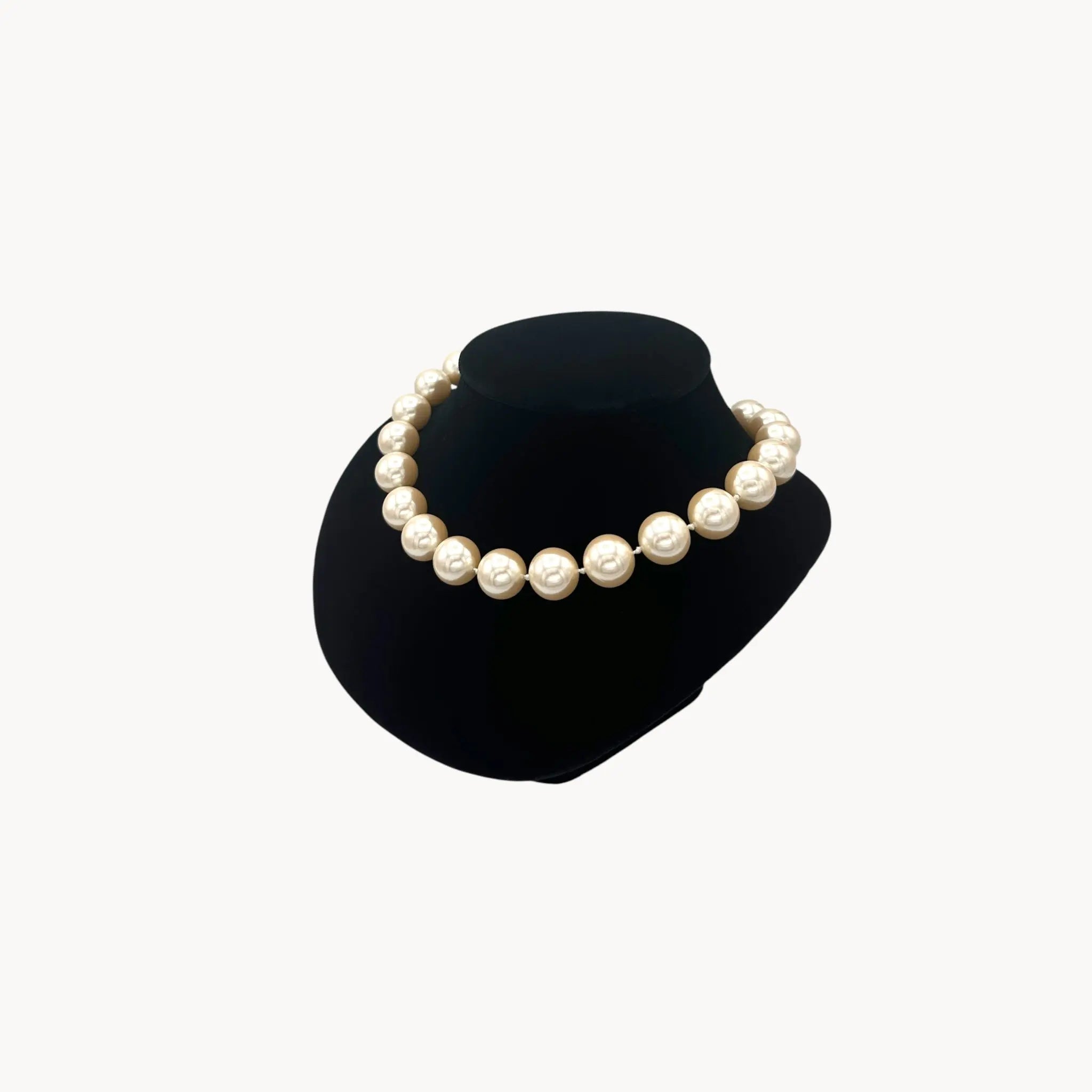 Side view of Carolee statement faux pearl strand necklace adjustable on black bust.
