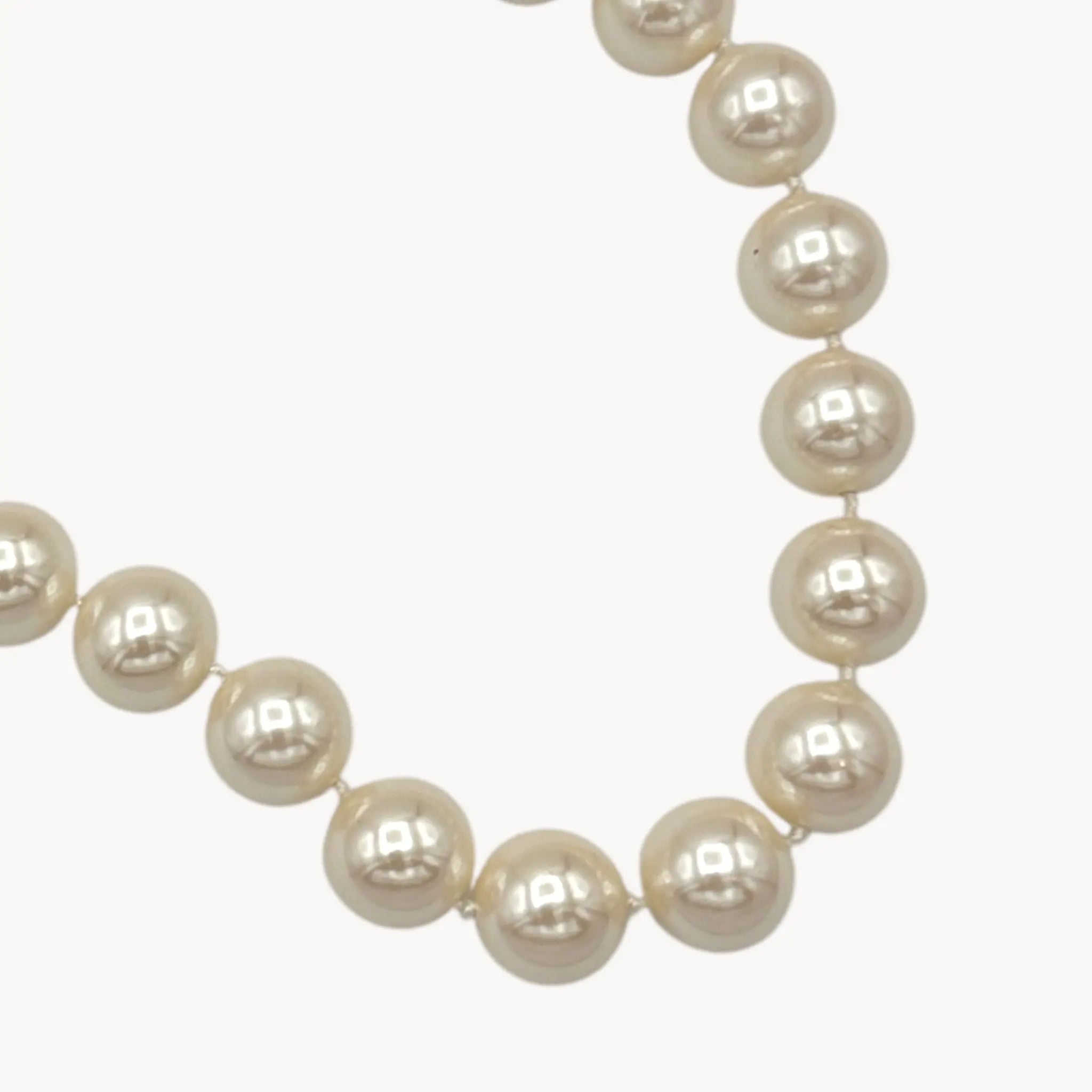 Close up view of 'pearls' of Carolee statement faux pearl strand necklace adjustable on white background.