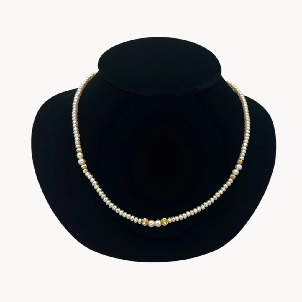 Close up the view of Classic pearl and 14K gold bead strand necklace, vintage fine jewelry on black bust.