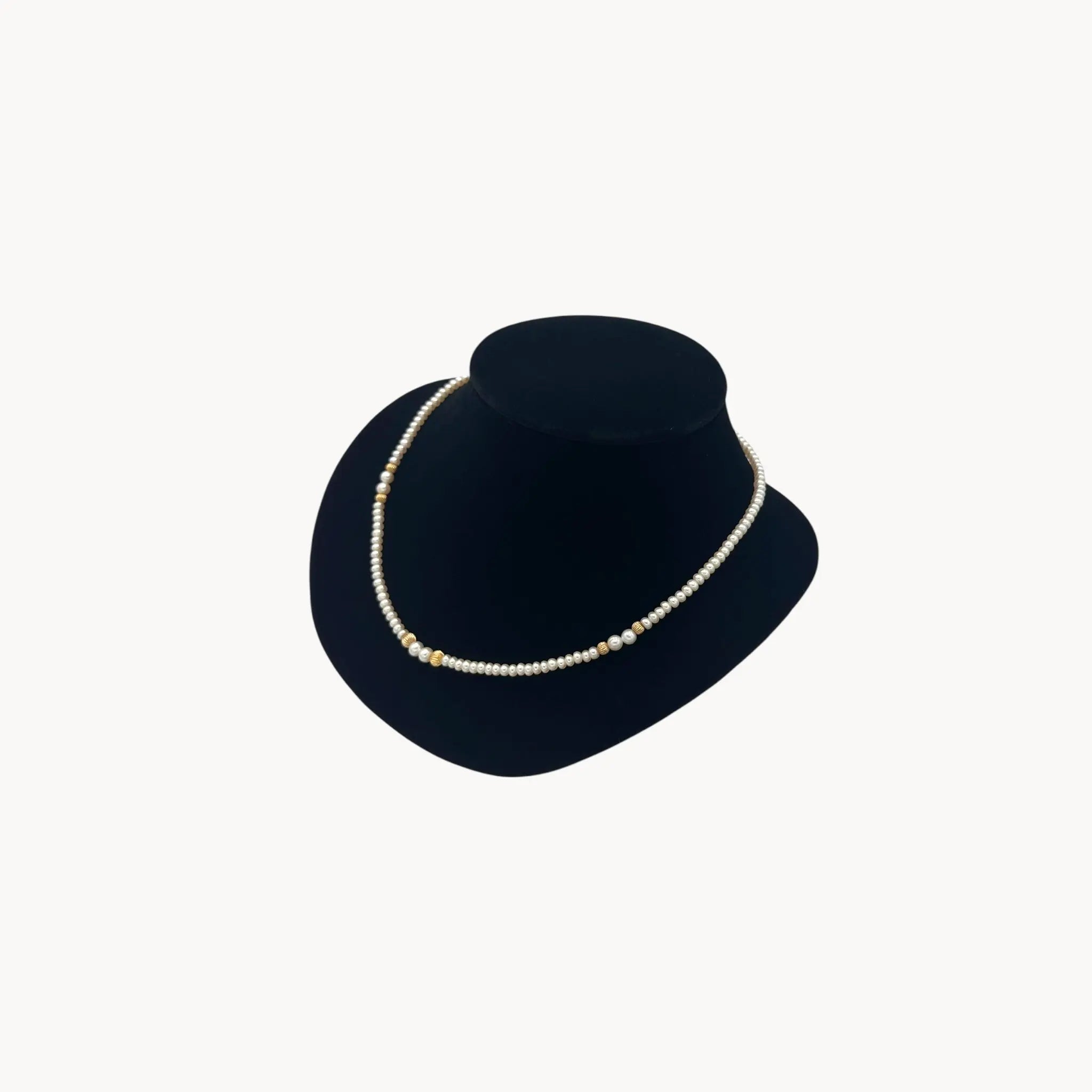 Side view of Classic pearl and 14K gold bead strand necklace, vintage fine jewelry on black bust.