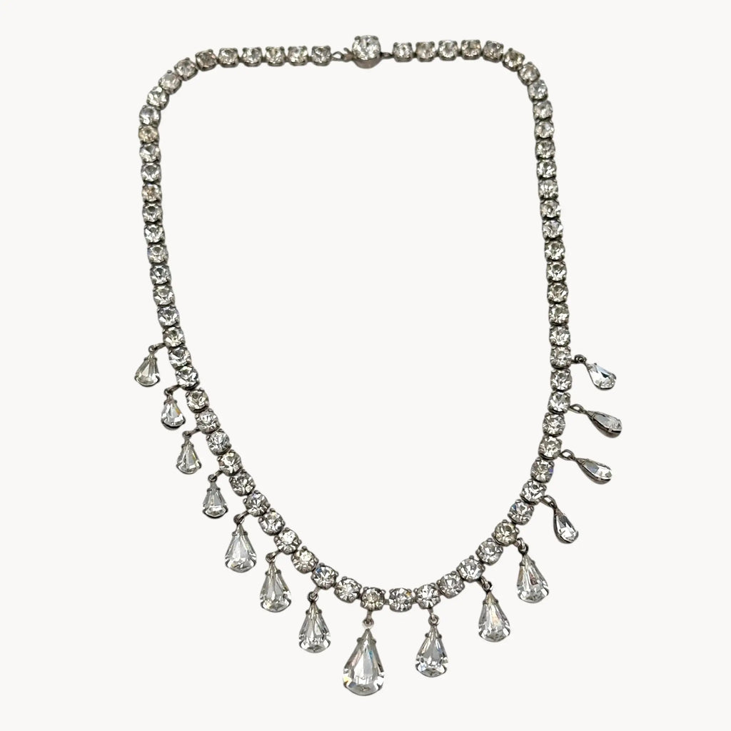 Close up view of Coro sterling silver Art Deco necklace with teardrop rhinestone pendant on white background.