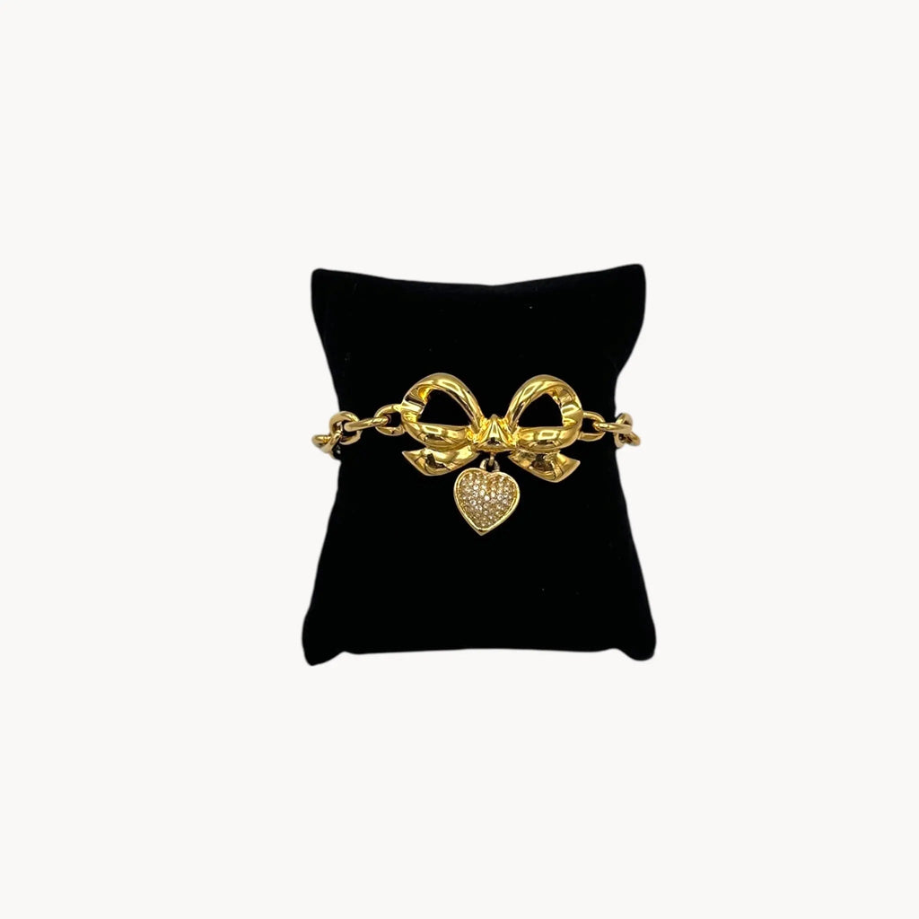Front view of Elizabeth Taylor gold-tone bow and pave heart bracelet on black pillow.