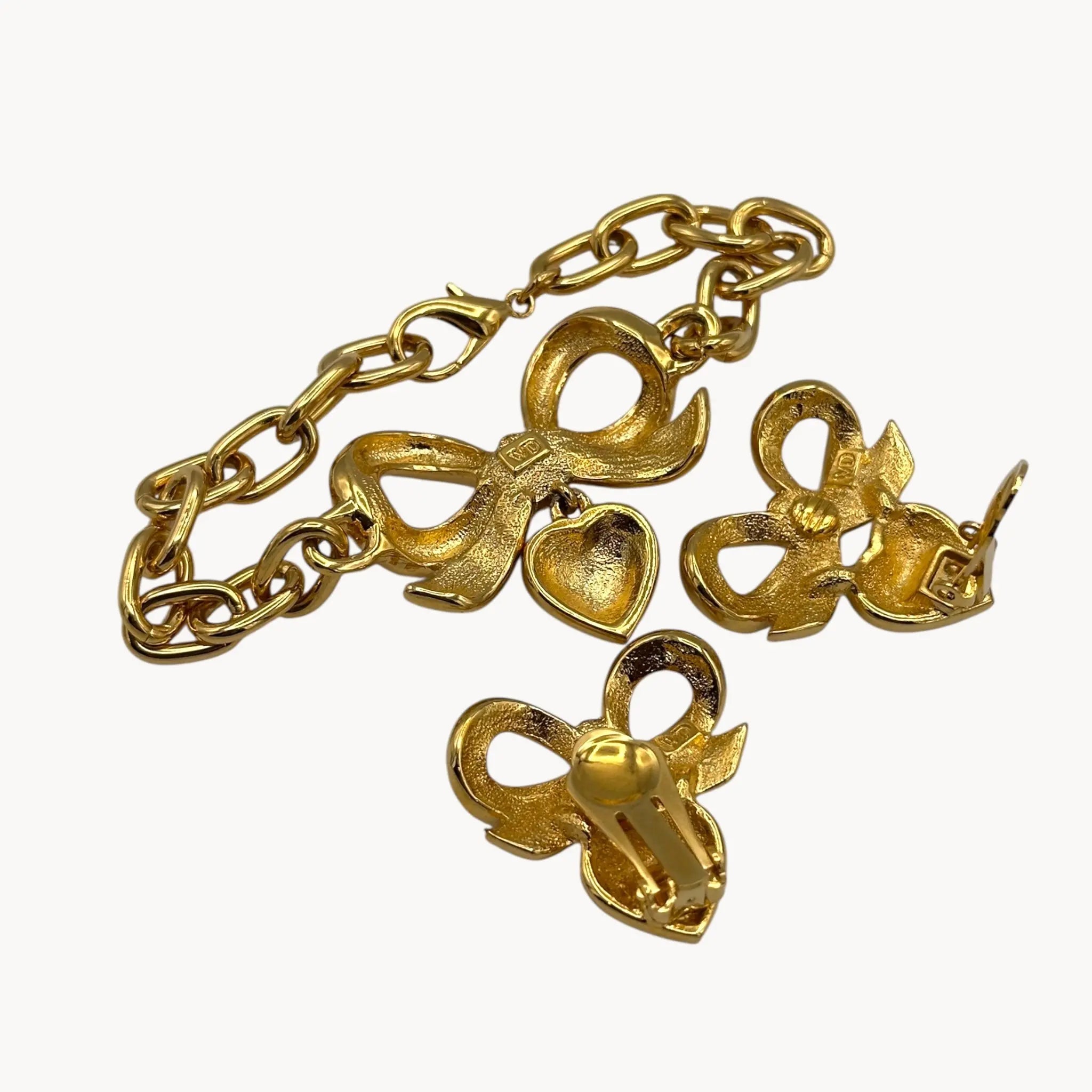 Full back view of Close up view of Elizabeth Taylor gold-tone bow and pave heart bracelet and earrings on white background.