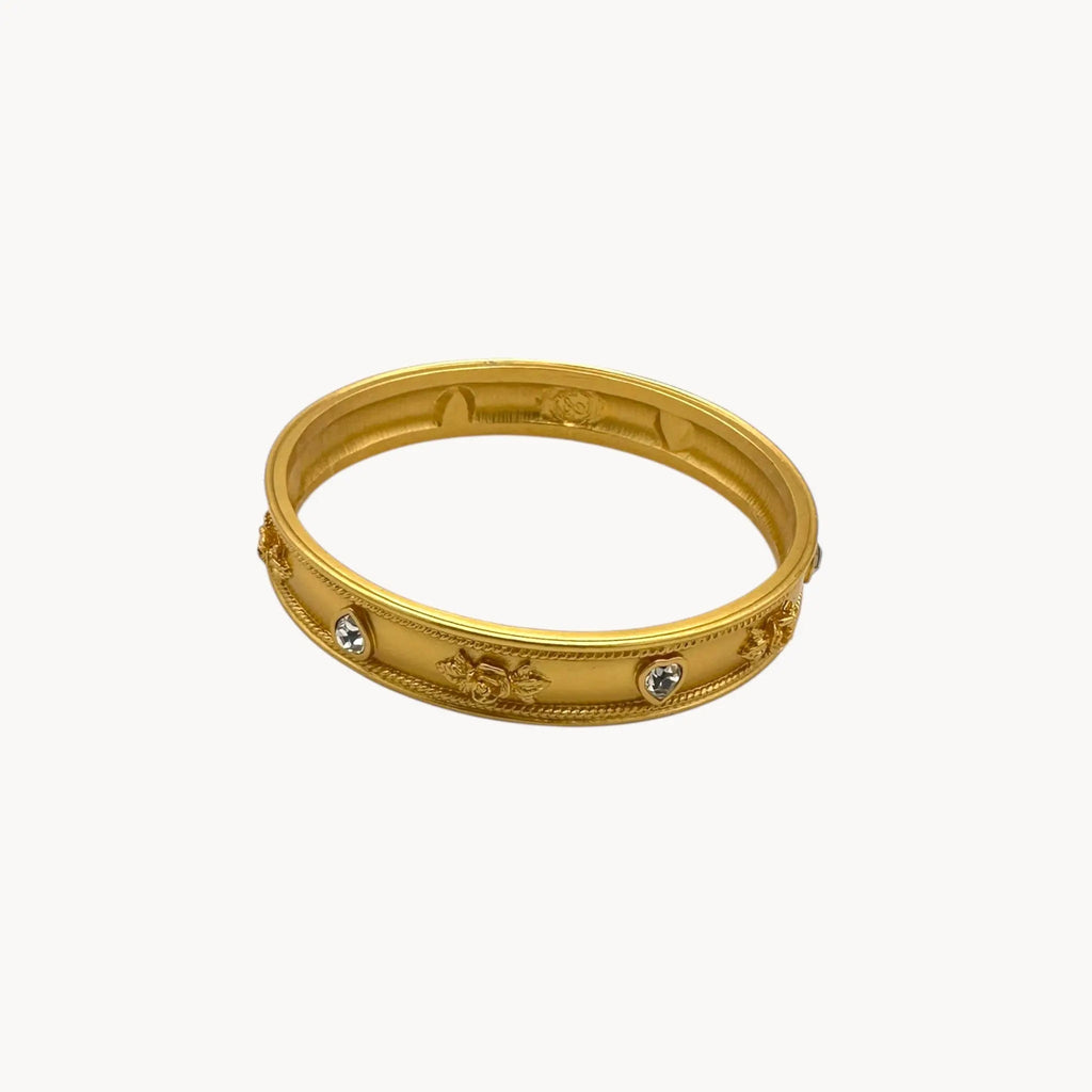 Against white background Elizabeth Taylor Love Blooms gold bangle bracelet with crystal heart and floral accents.