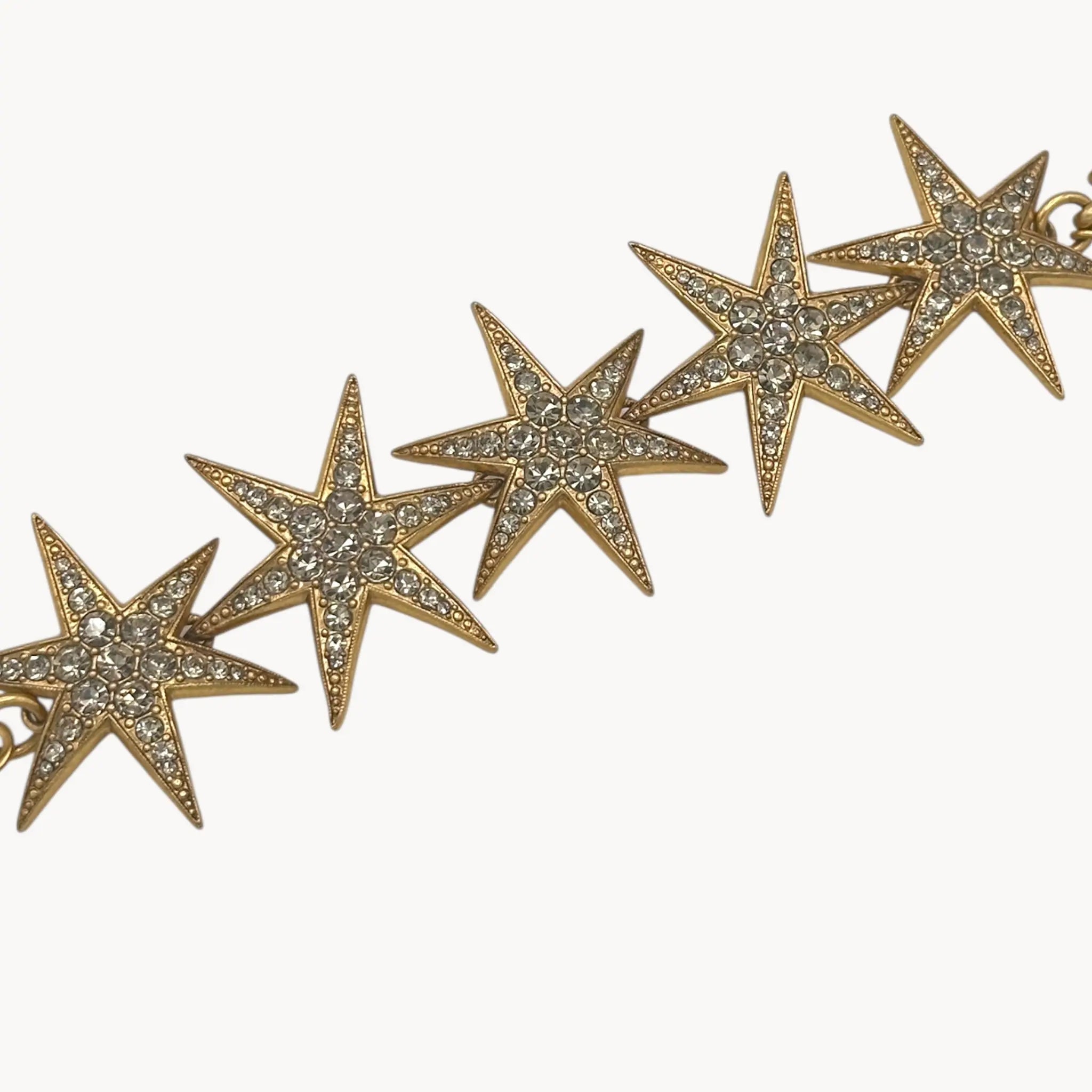 Close up of stars of J. Crew gold-tone Art Deco style star bracelet with crystal accents on white background.