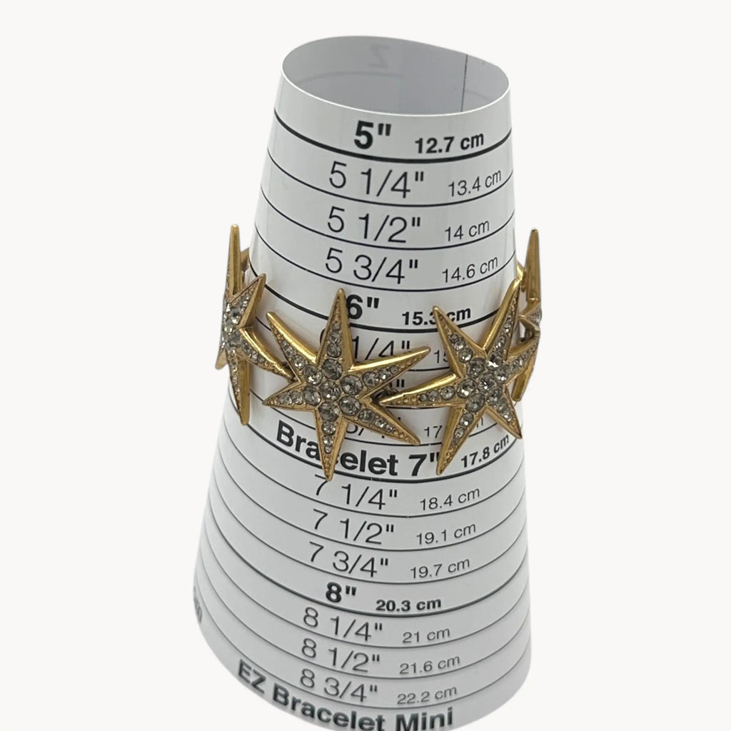 On sizer view of J. Crew gold-tone Art Deco style star bracelet with crystal accents on white background.