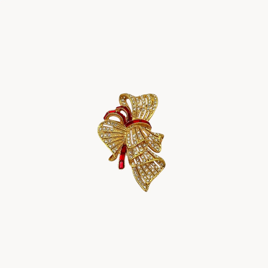 Side view of Jacqueline Bouvier Kennedy Camrose & Kross gold bow brooch with crystals and red rhinestones.