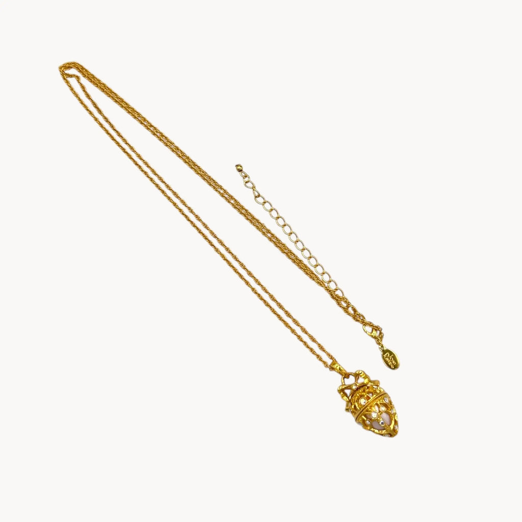 Flat lay against white background of Joan Rivers gold egg locket necklace on long chain