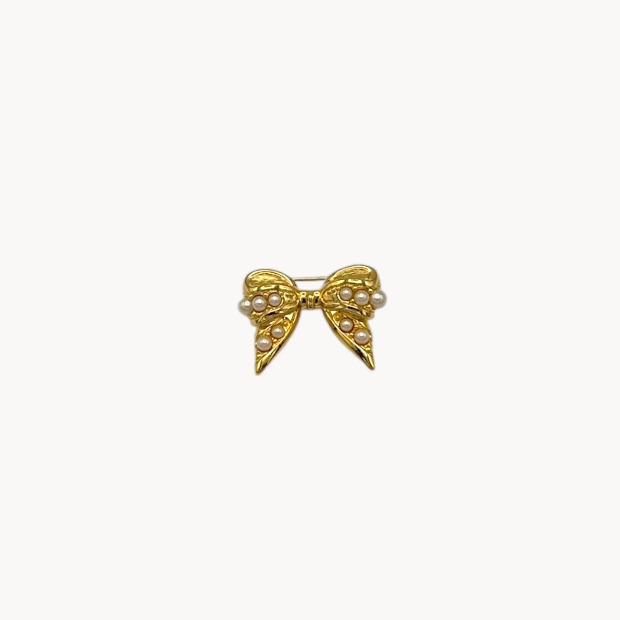 Close up view of Joan Rivers gold-tone bow brooch with petite faux pearls, vintage jewelry.