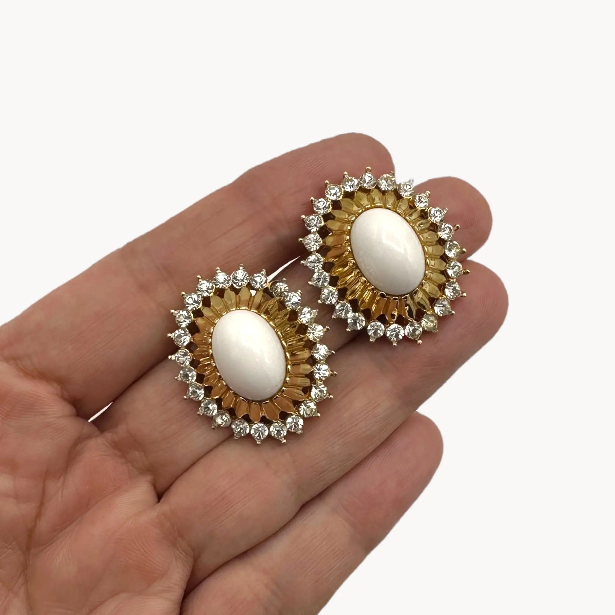 Gold Joseph Mazer Jomaz White Cabochon & Rhinestone Earrings shown on hand for scale on white background.